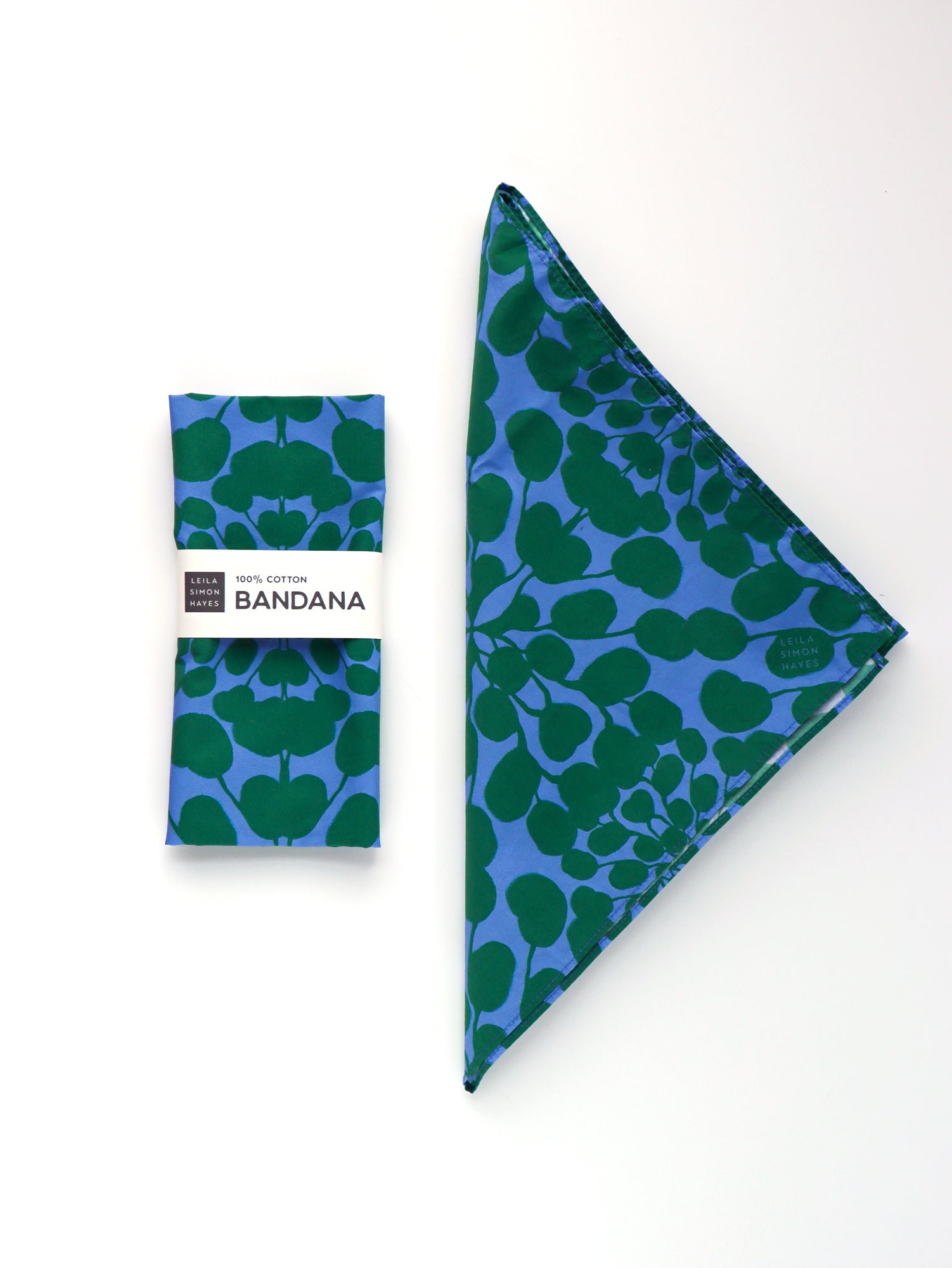 Blue bandana with green leaf pattern on a white background. Designed by artist Leila Simon Hayes.