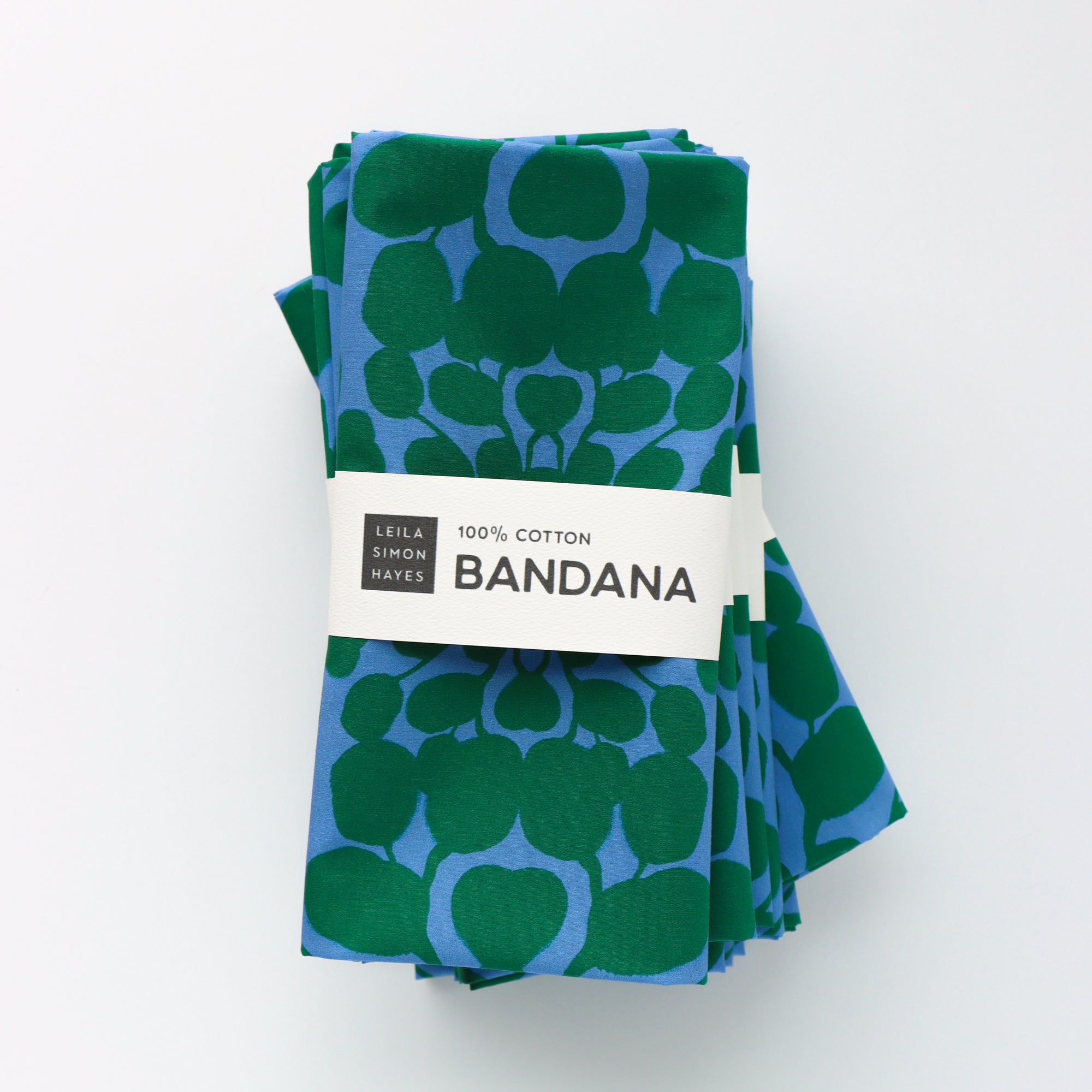 Green and blue patterned bandana with a brand label on a white background. Designed by artist Leila Simon Hayes.