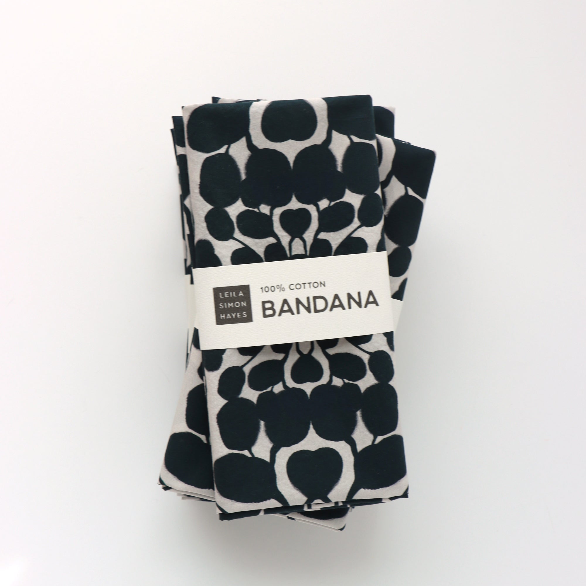 Folded bandana with black floral pattern and visible brand label on a white background. Designed by artist Leila Simon Hayes.