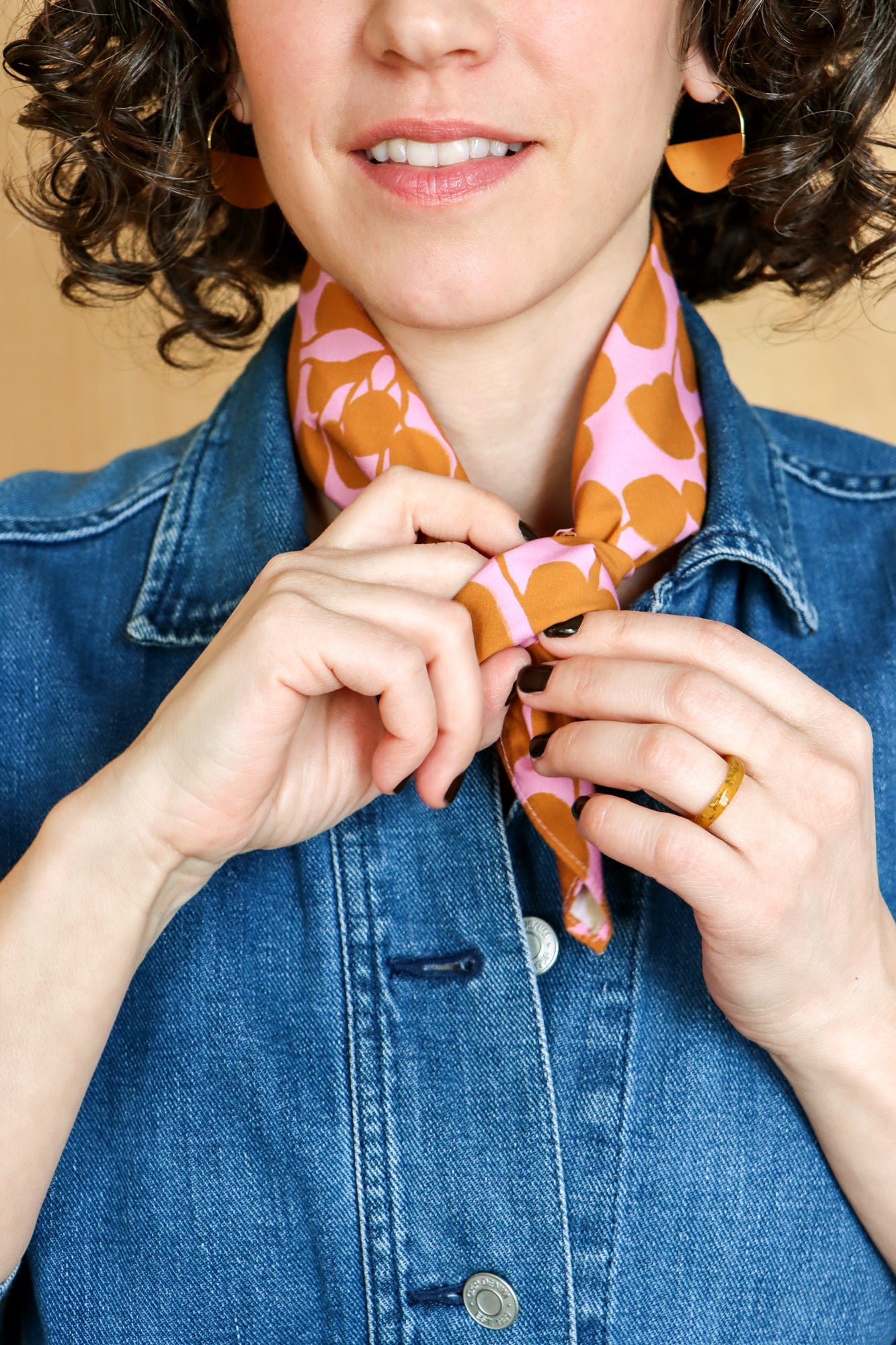 Person wearing a colorful bandana and blue denim jacket against a beige background. Designed by artist Leila Simon Hayes.