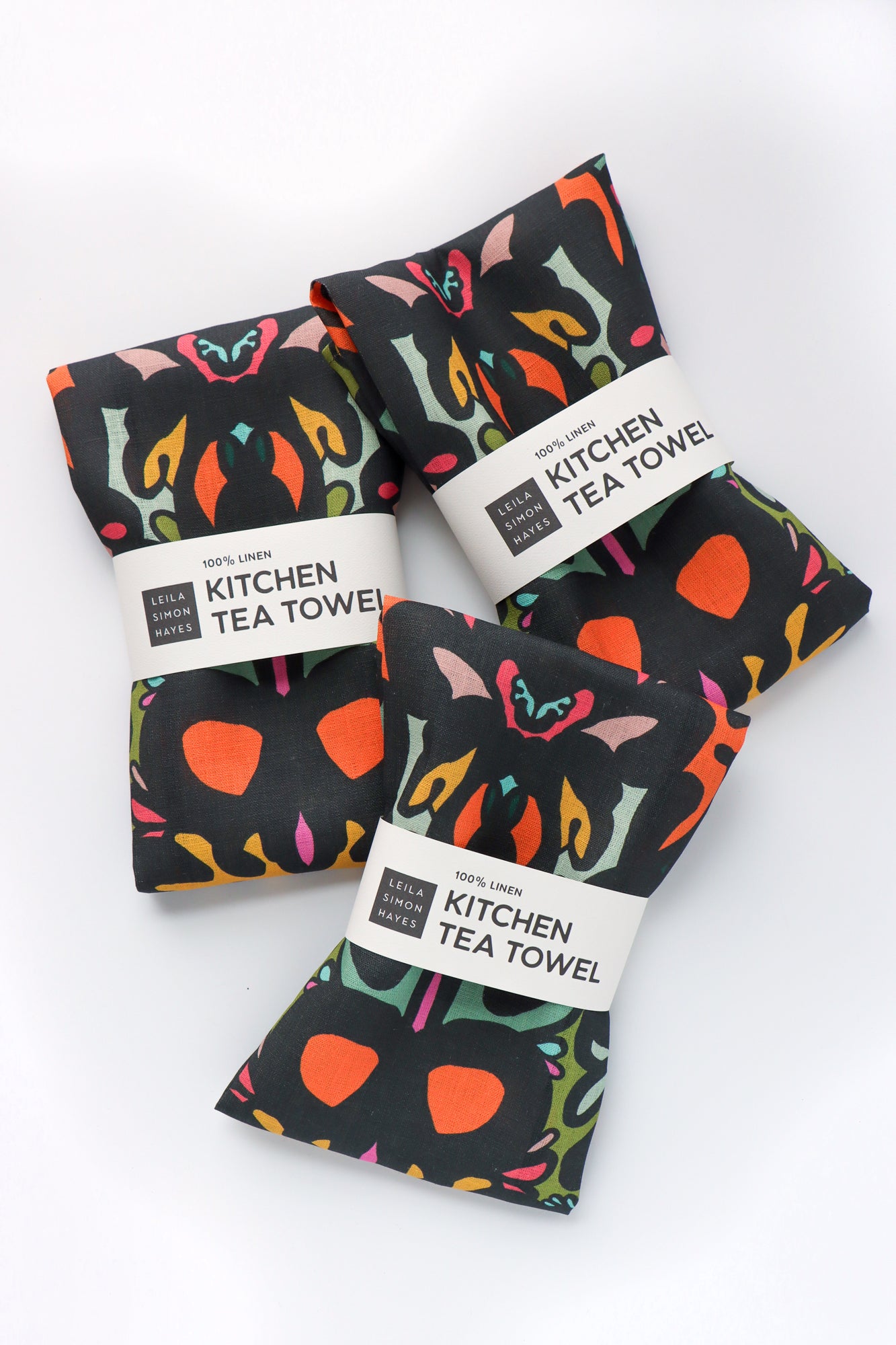 Three kitchen tea towels with colorful damask pattern on a white background. Designed by artist Leila Simon Hayes.
