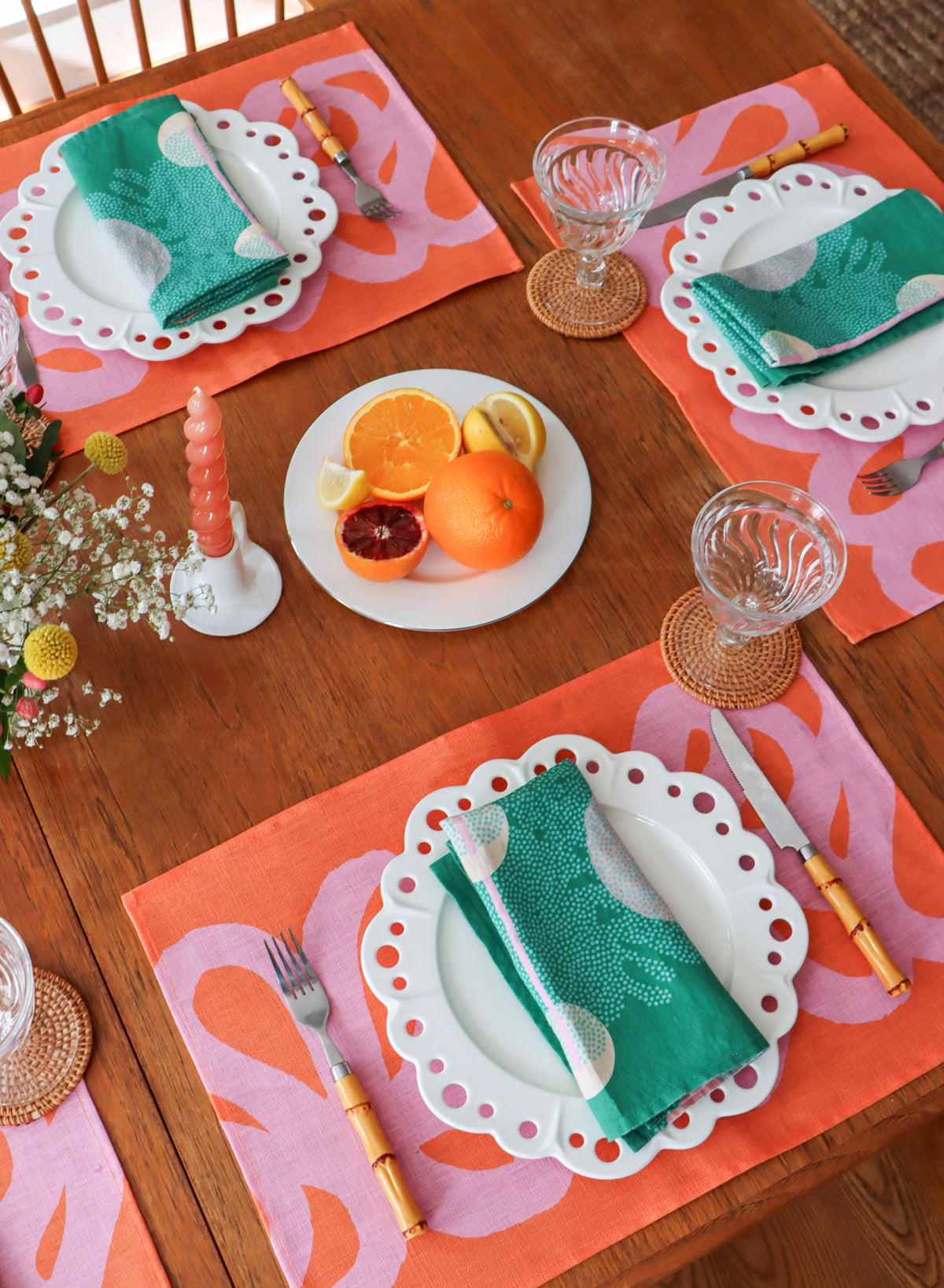 Teal napkins on a pink and coral placemat set up for a nice dinner. Table linens designed by artist Leila Simon Hayes