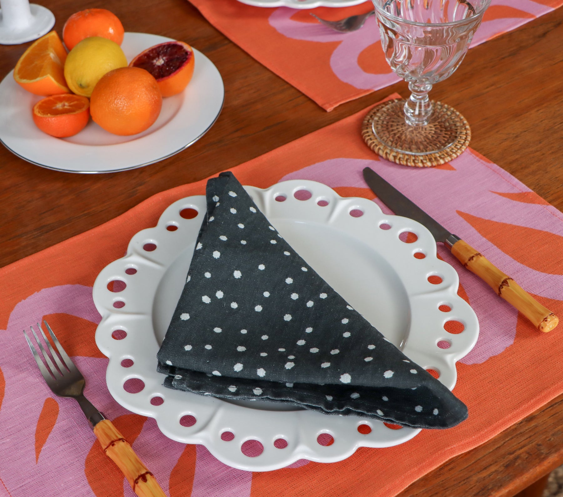 A black and white polka dot napkin over a coral and pink placemat, designed by artist Leila Simon Hayes