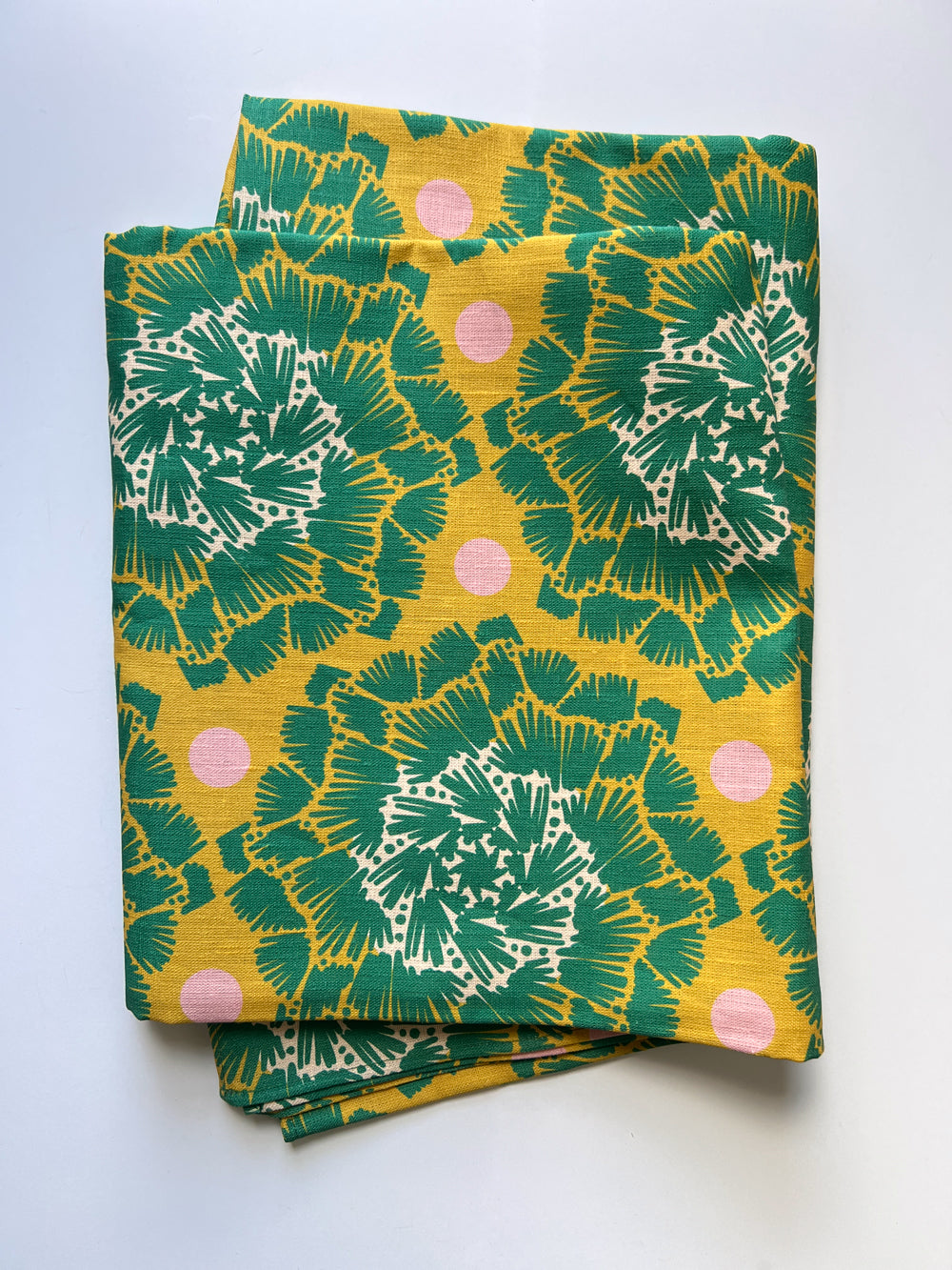A tablecloth with green floral patterns on a white background designed by artist Leila Simon Hayes