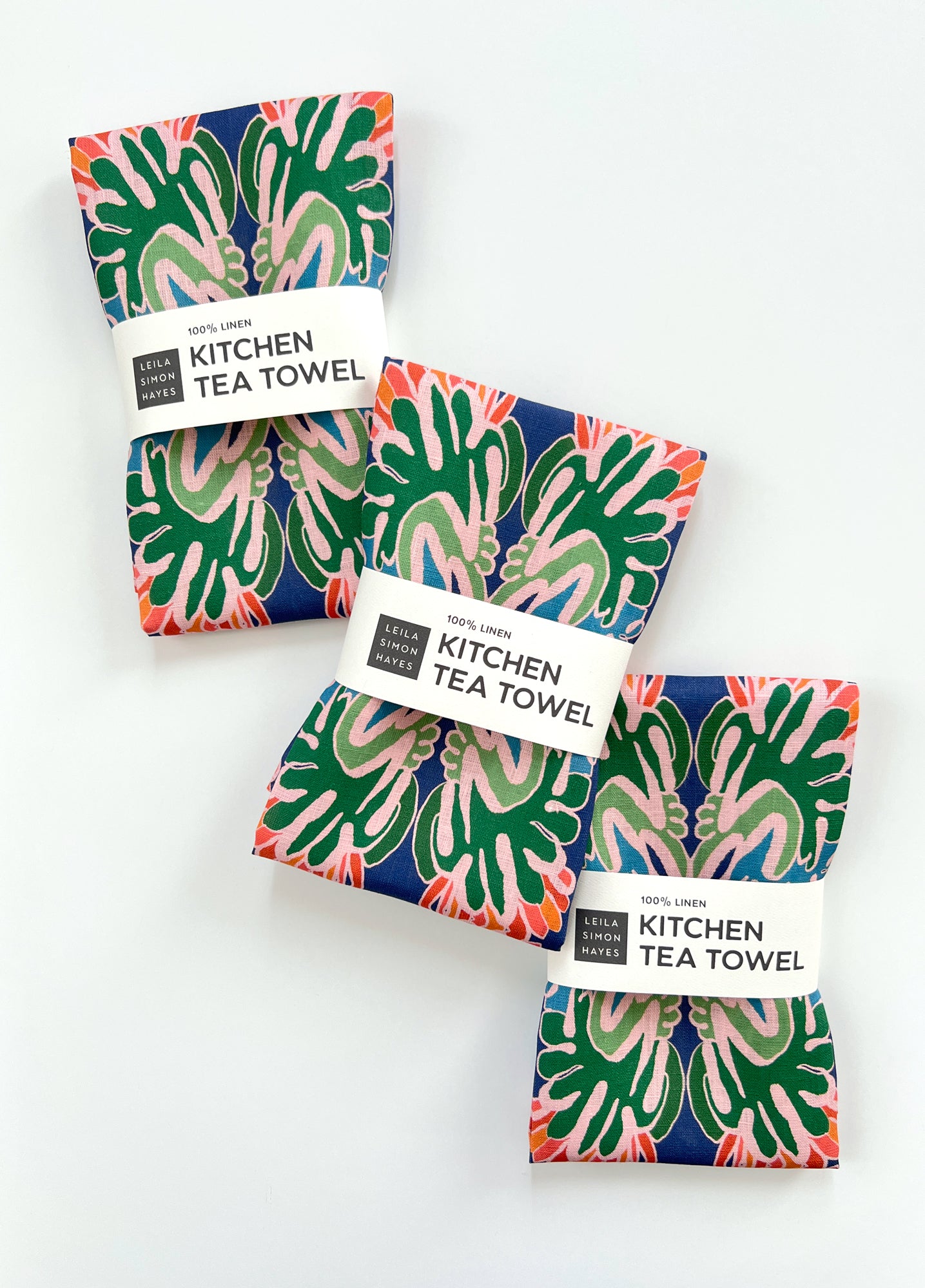 Three kitchen tea towels with tropical  floral patterns on a white background. Designed by artist Leila Simon Hayes.