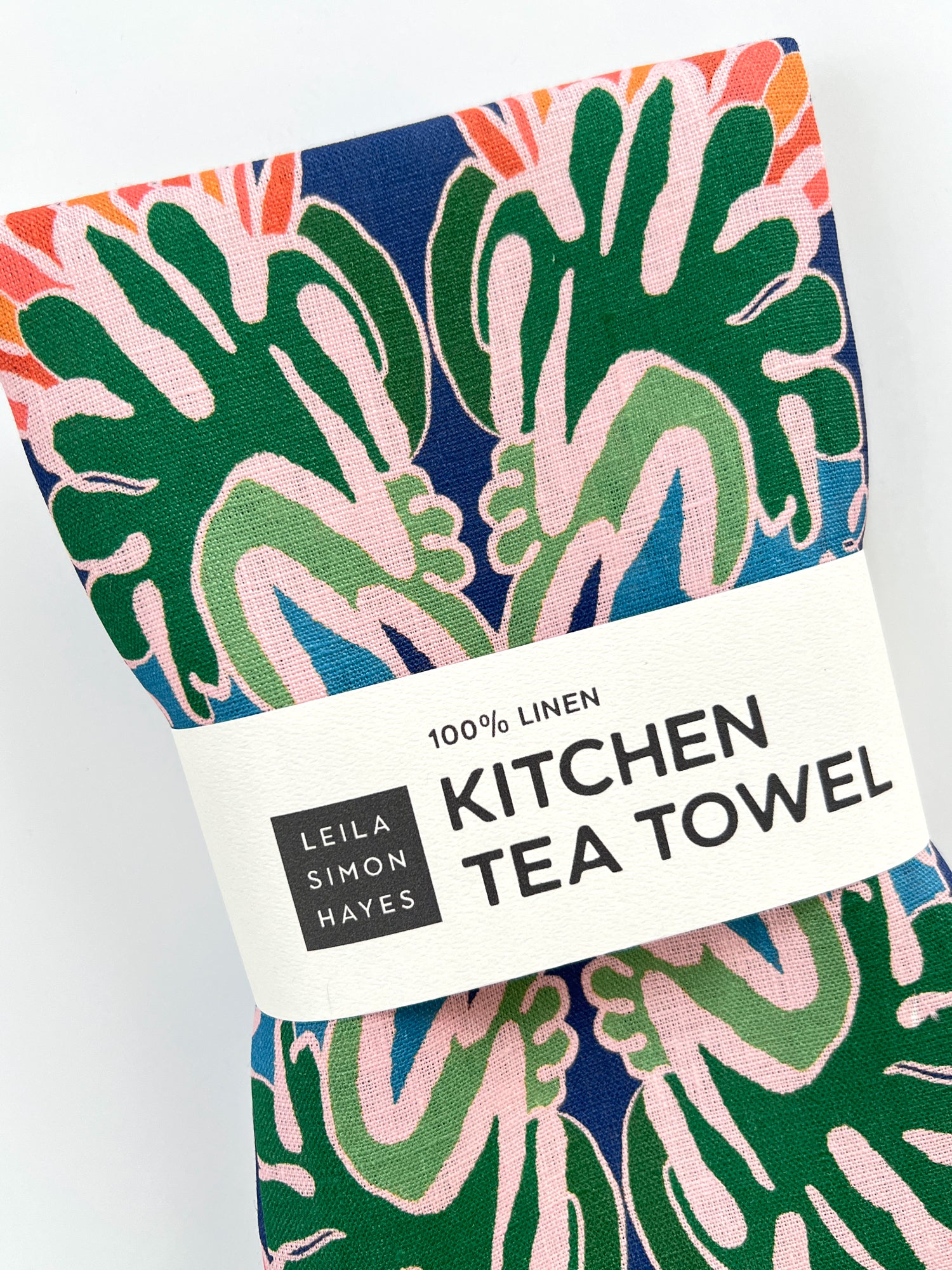 Kitchen tea towel with leaf pattern and Leila Simon Hayes branding on a white background. Designed by artist Leila Simon Hayes.