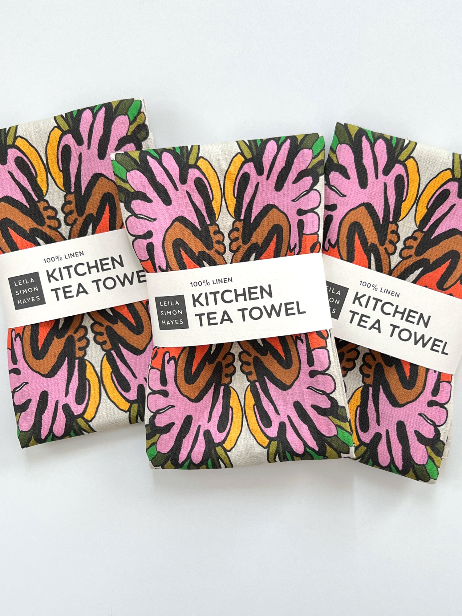 Three kitchen tea towels with colorful abstract patterns on a white background. Designed by artist Leila Simon Hayes.