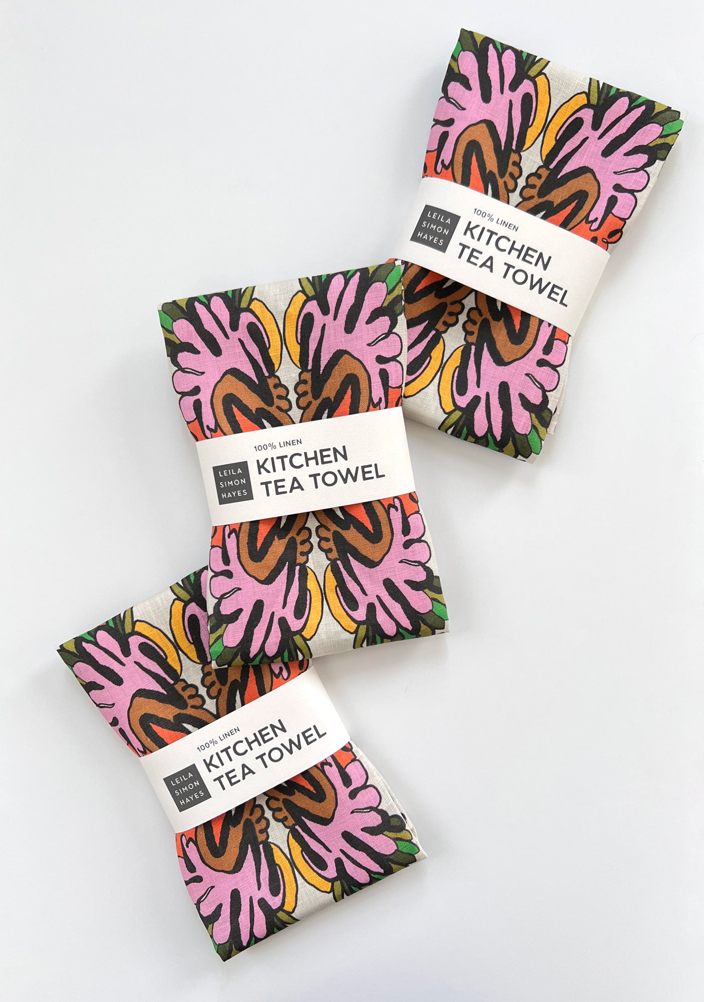 Three colorful kitchen tea towels with abstract patterns on a white background. Designed by artist Leila Simon Hayes.