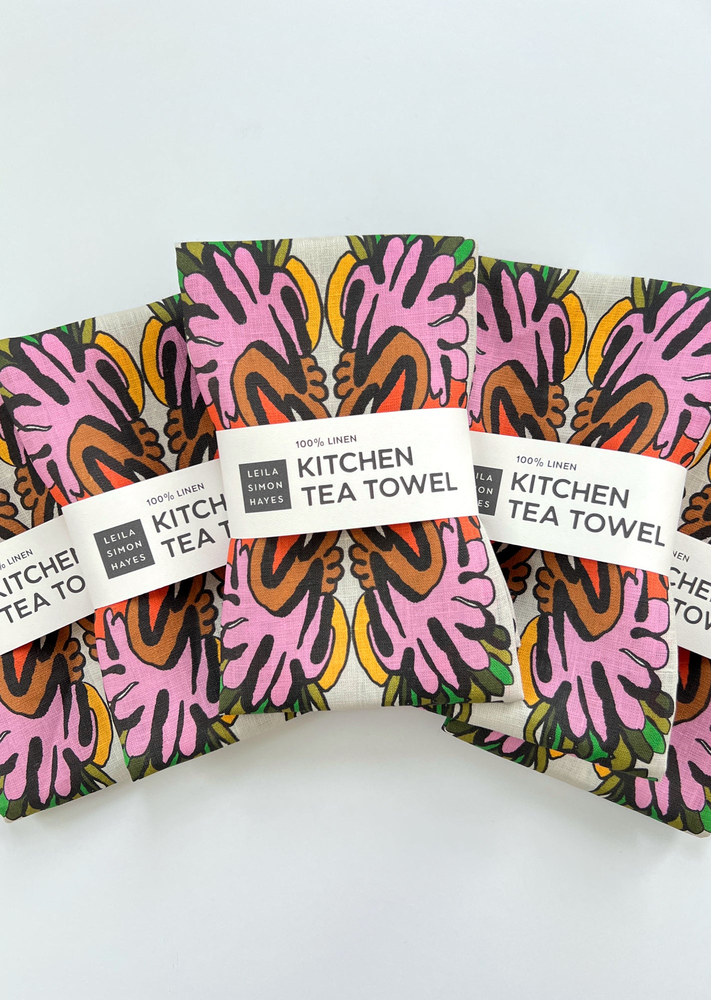 Set of colorful kitchen tea towels with patterned design on a white background. Designed by artist Leila Simon Hayes.