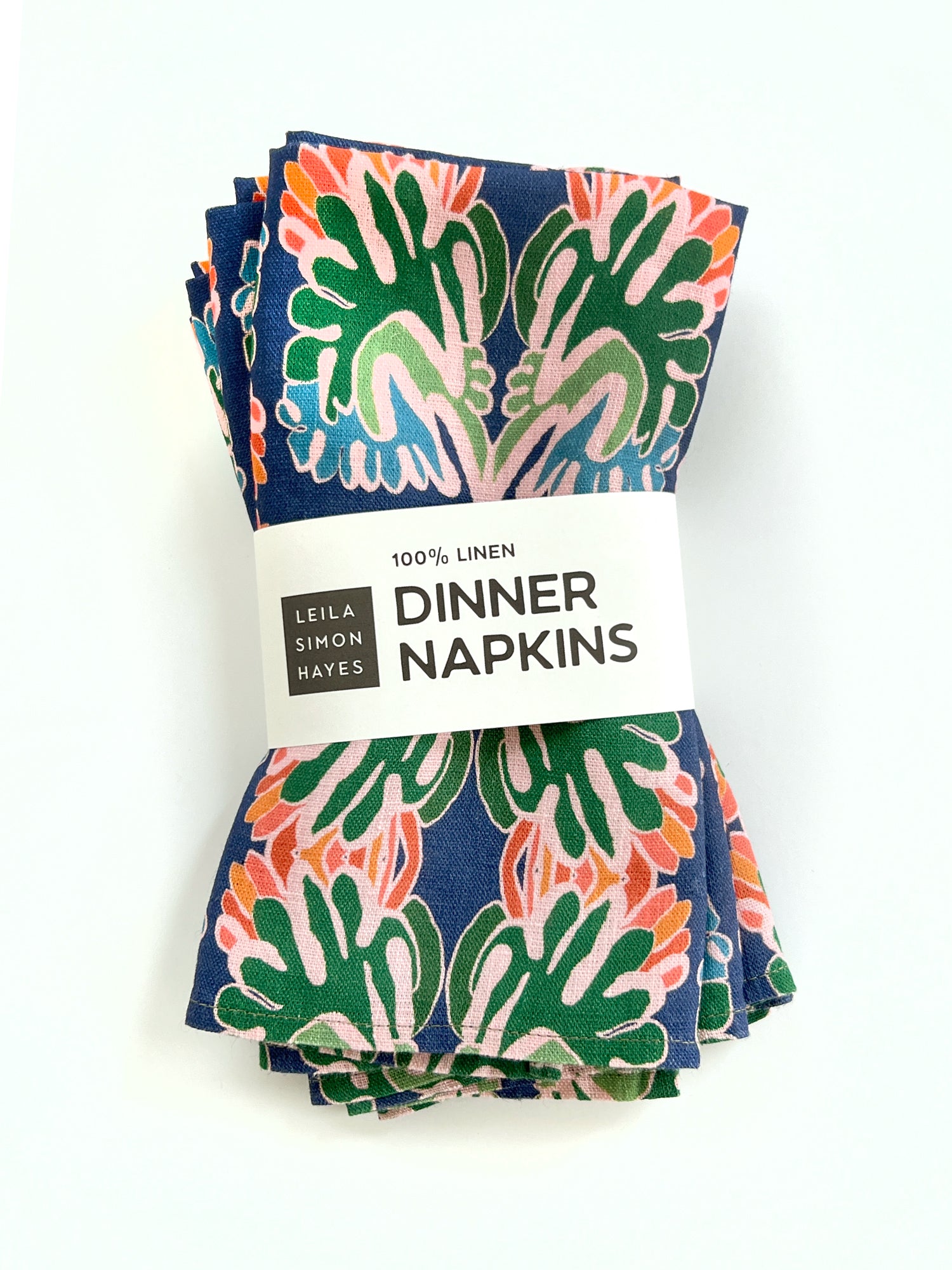 Set of colorful linen dinner napkins with a '100% Linen Dinner Napkins' label designed by Leila Simon Hayes on a white background