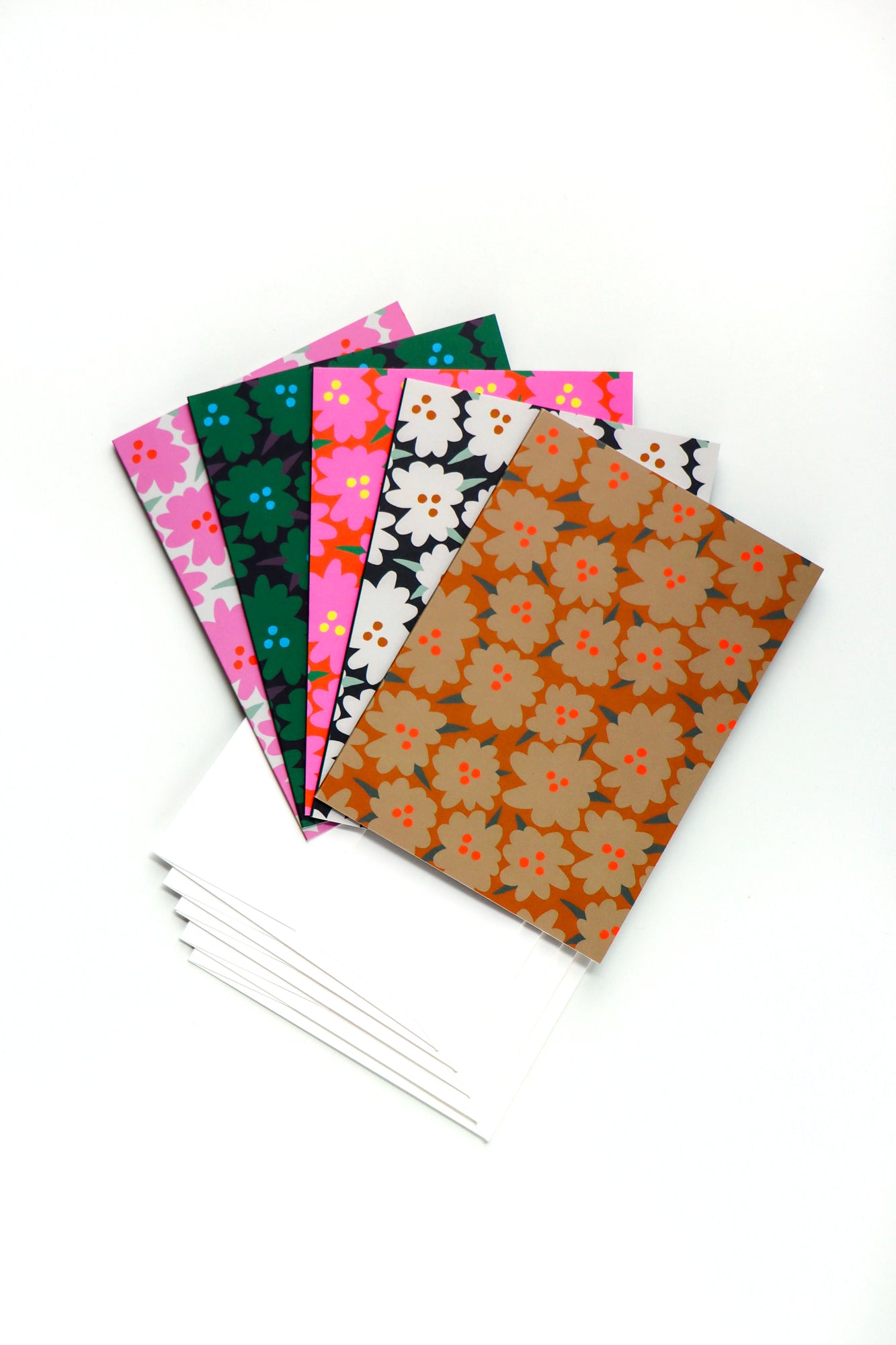 Pack of five abstract floral folded cards in different colors with matching white envelopes on a white background. Designed by artist Leila Simon Hayes.