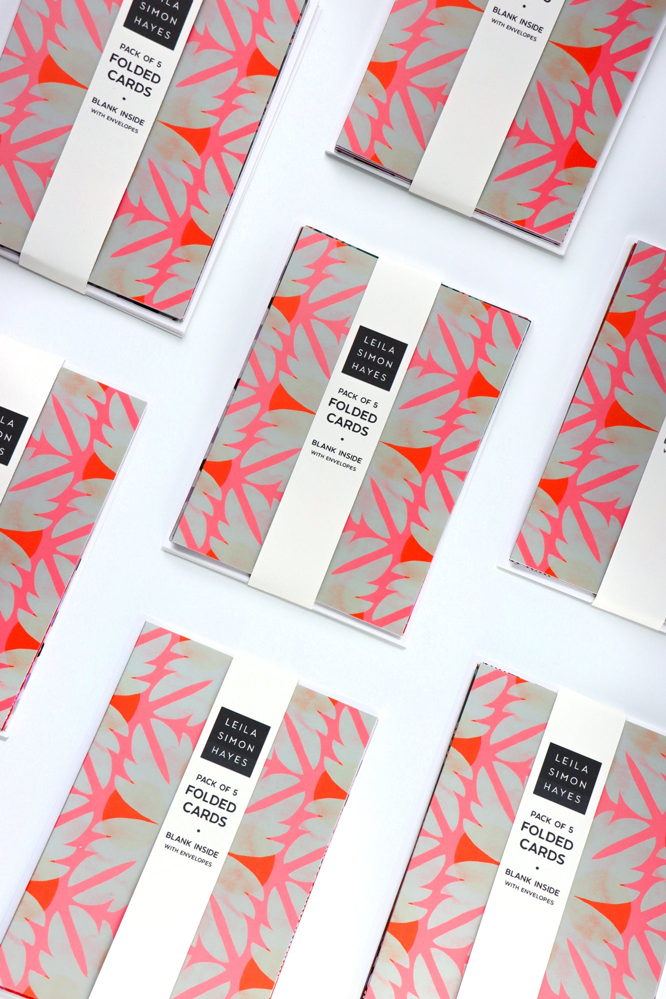 Pack of five abstract patterned folded cards with a white envelope on a white background. Designed by artist Leila Simon Hayes.