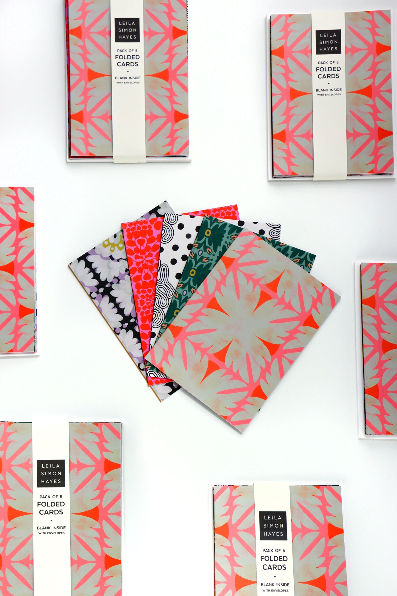 Pack of five abstract patterned folded cards with a white envelope on a white background. Designed by artist Leila Simon Hayes.