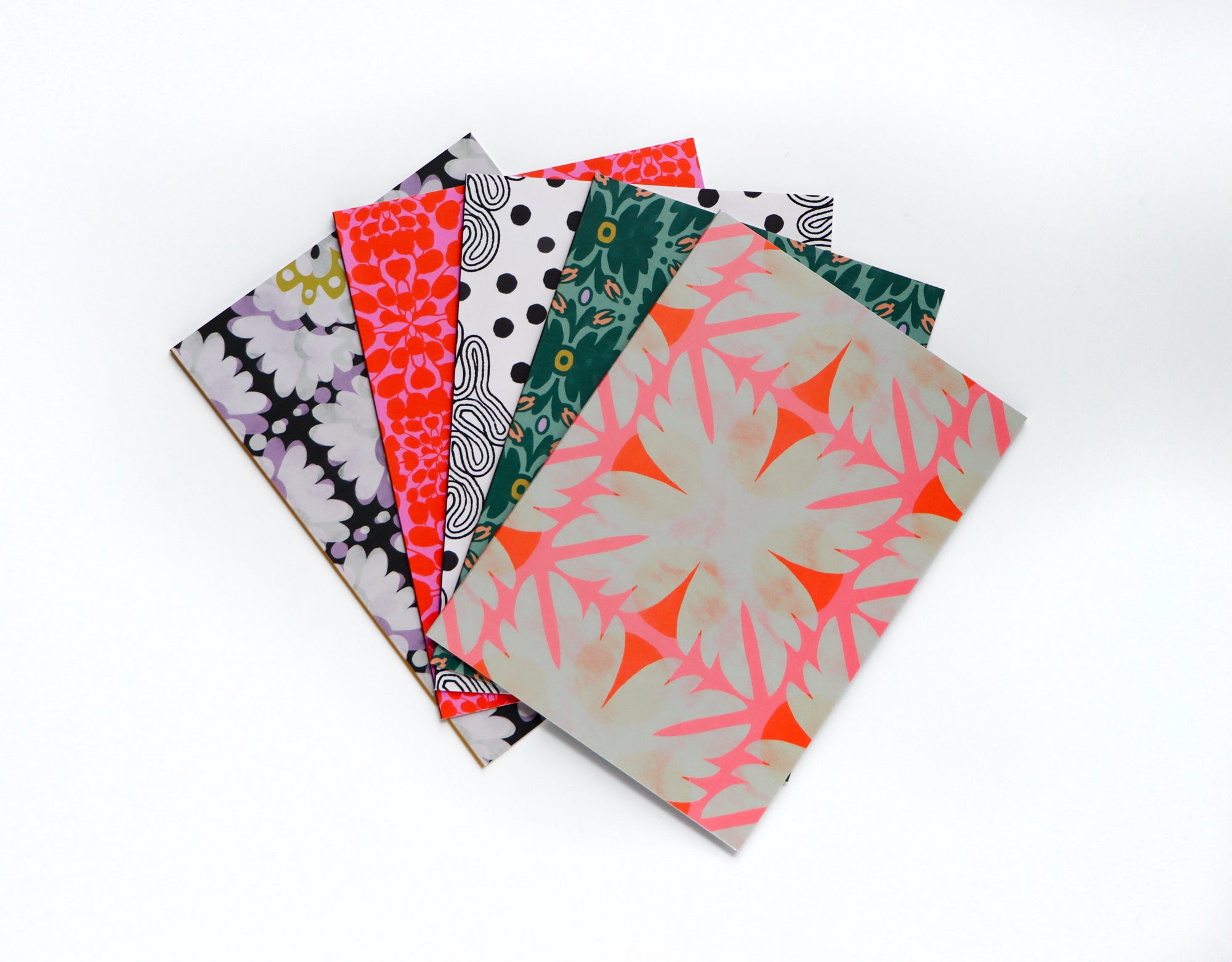 Five patterned folded cards, designed by artist Leila Simon Hayes, stacked on a white background. 