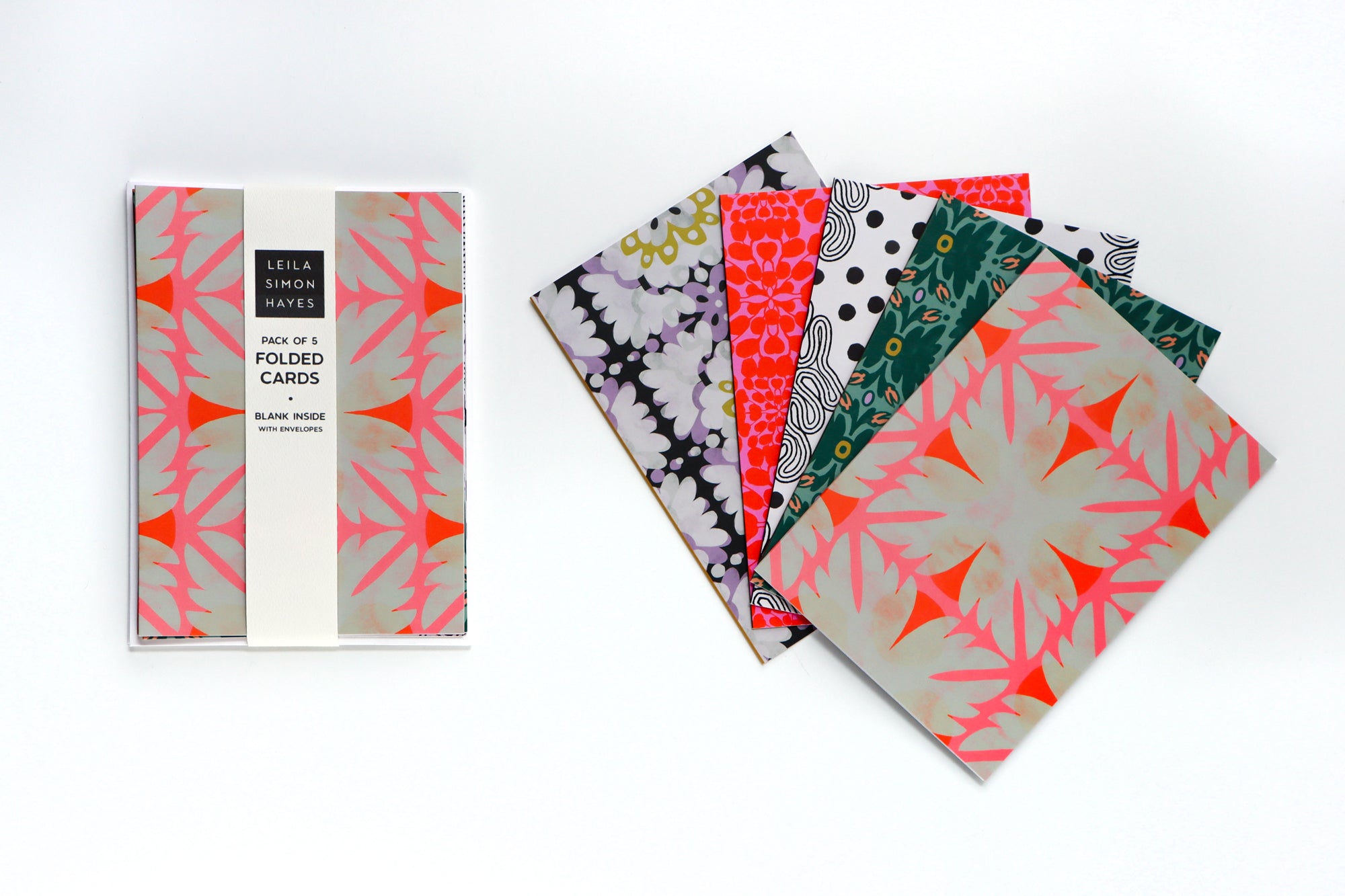 Set of five folded cards with geometric and floral patterns on a white background, designed by artist Leila Simon Hayes.