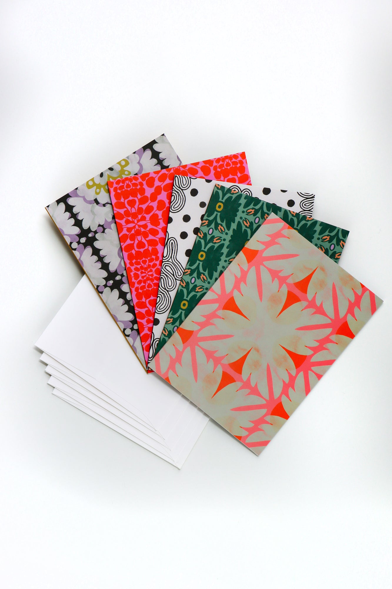 Pack of five abstract patterned folded cards with a white envelope on a white background. Designed by artist Leila Simon Hayes.