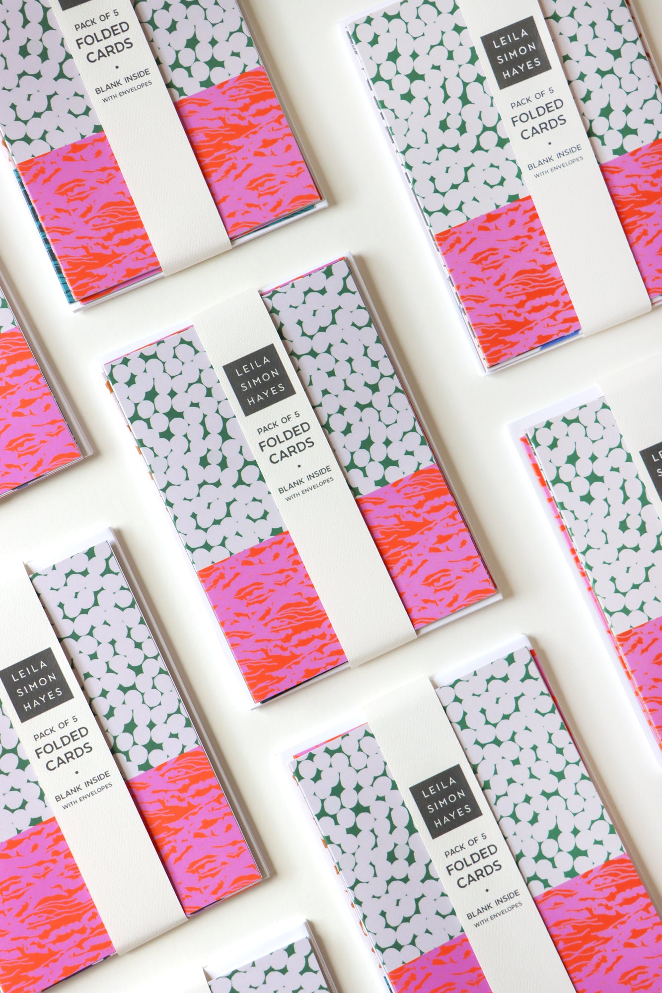 Packaged folded card packs on display with a white background, designed by artist Leila Simon Hayes.