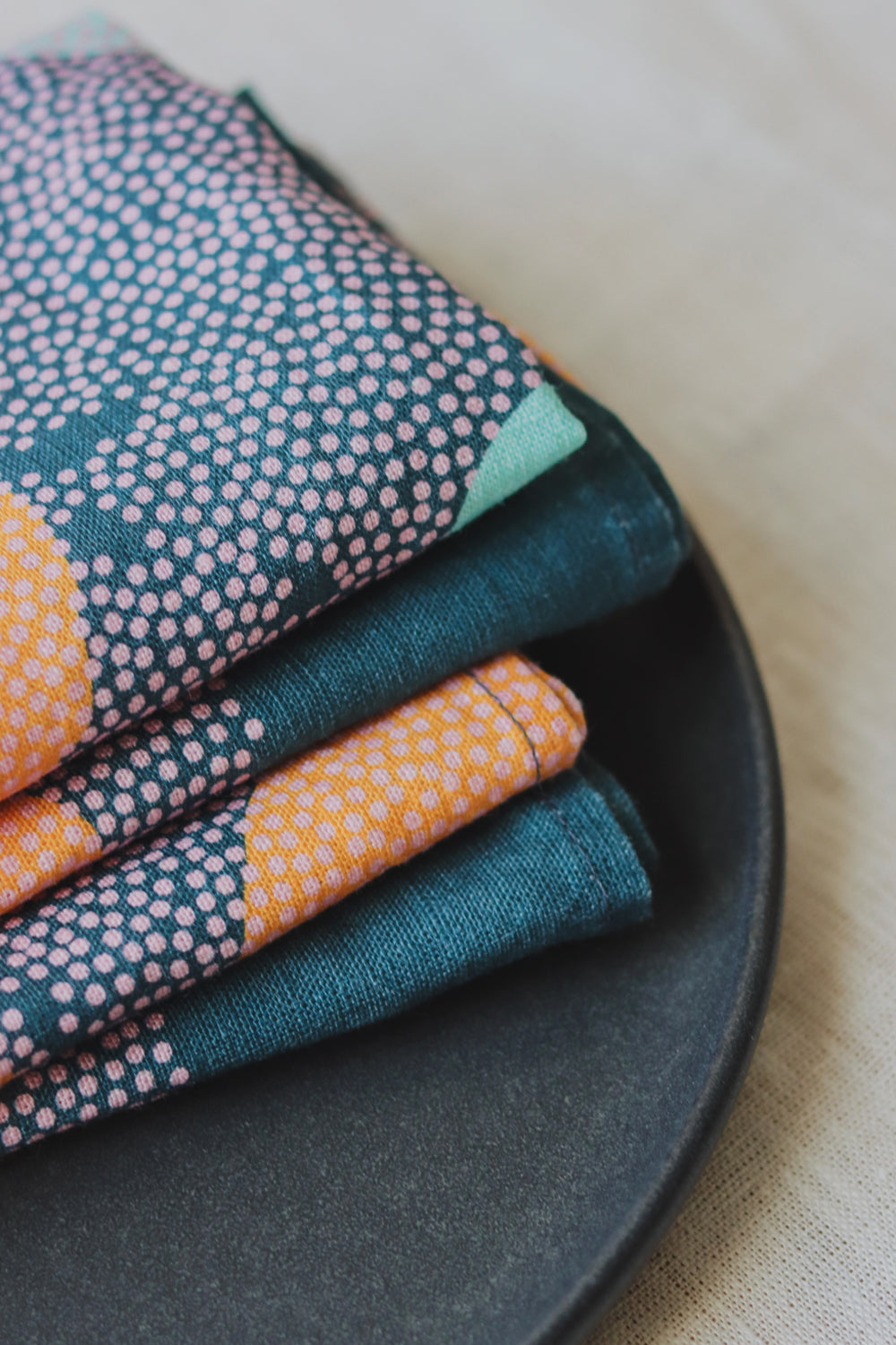 A close up image of four blue napkins folded and layered on a plate. Designed by artist Leila Simon Hayes. 