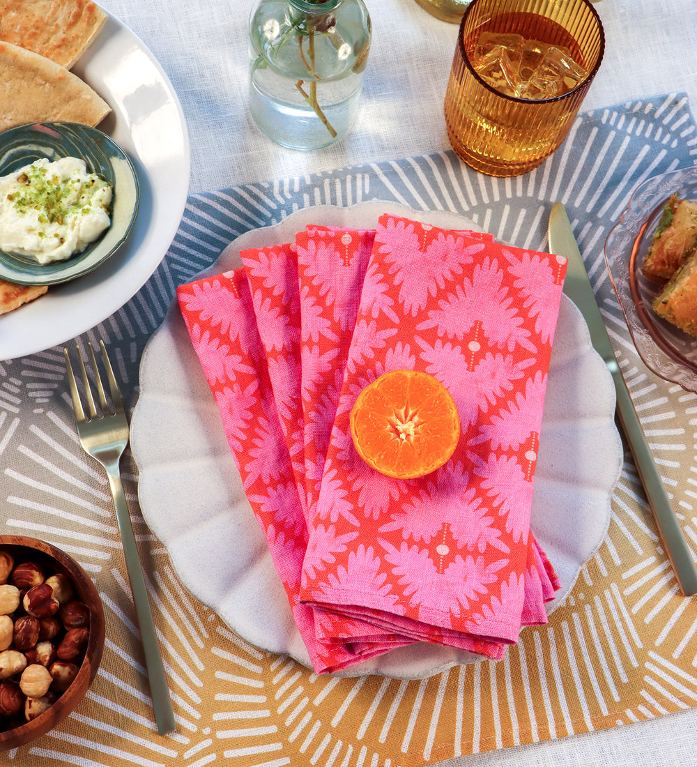 Designed by artist Leila Simon Hayes.  Four pink napkins on a white plate over an abstract placemat.