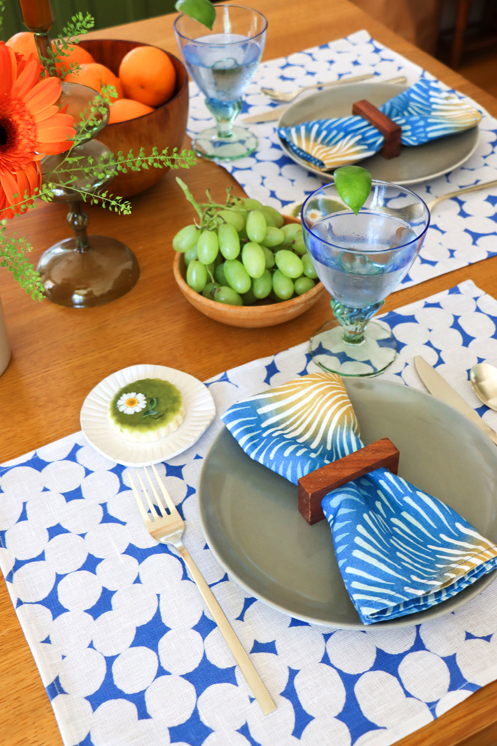 Dining table setting with blue burst napkins and blue and white dots patterned placemats. Designed by artist Leila Simon Hayes. 