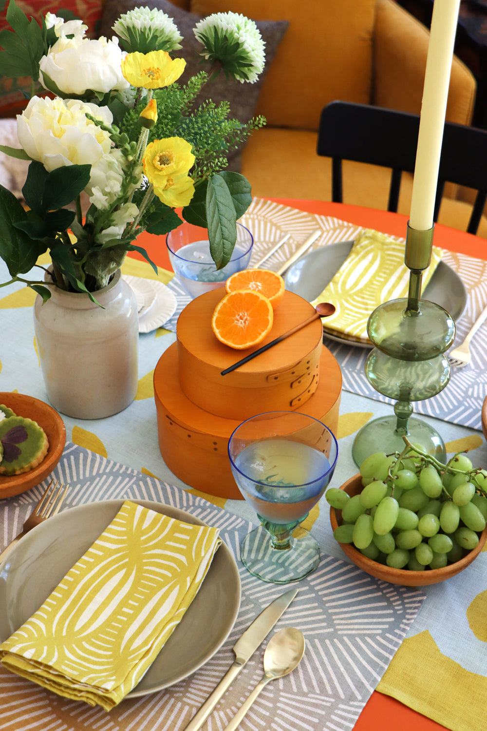 Decorative table setting with yellow striped dinner napkins, blue and yellow gradient placemats and a citron table runner. Designed by artist Leila Simon Hayes
