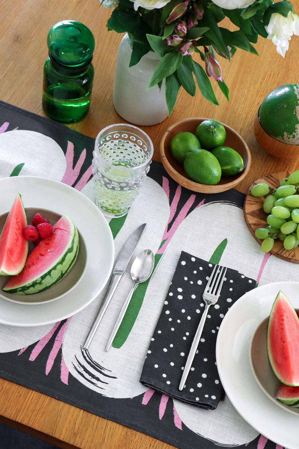 Dining table setting with black and white polka dotted napkins, over an abstract table runner. Designed by artist Leila Simon Hayes.