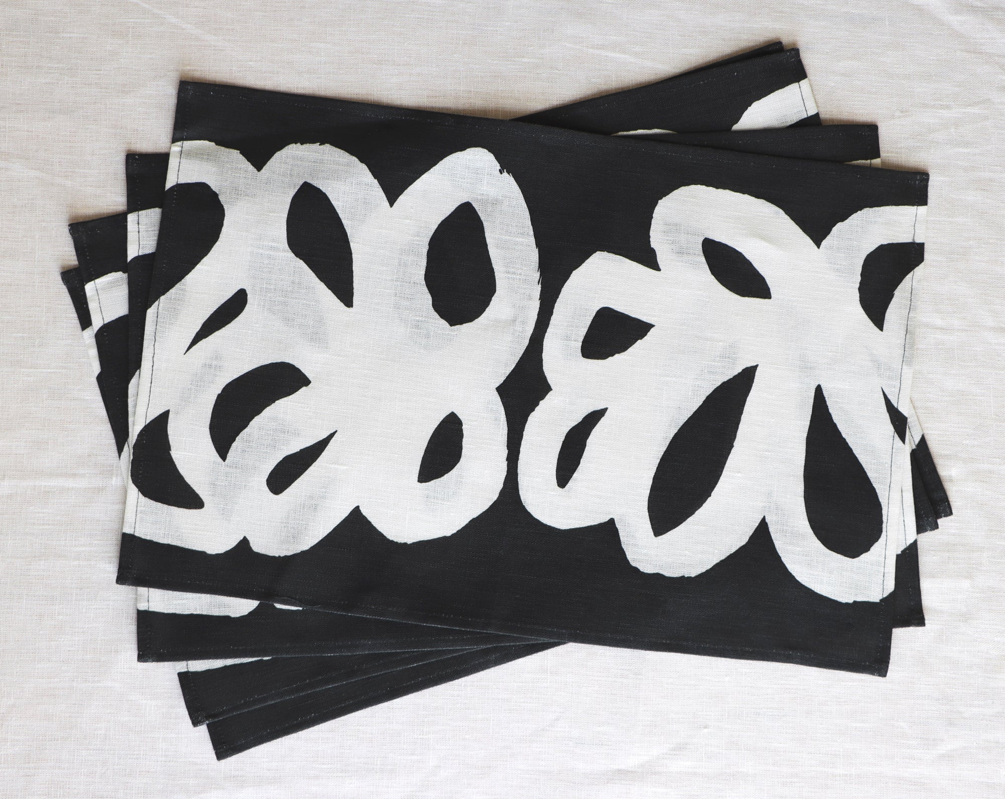 A stack of black and white placemats designed by artist Leila Simon Hayes