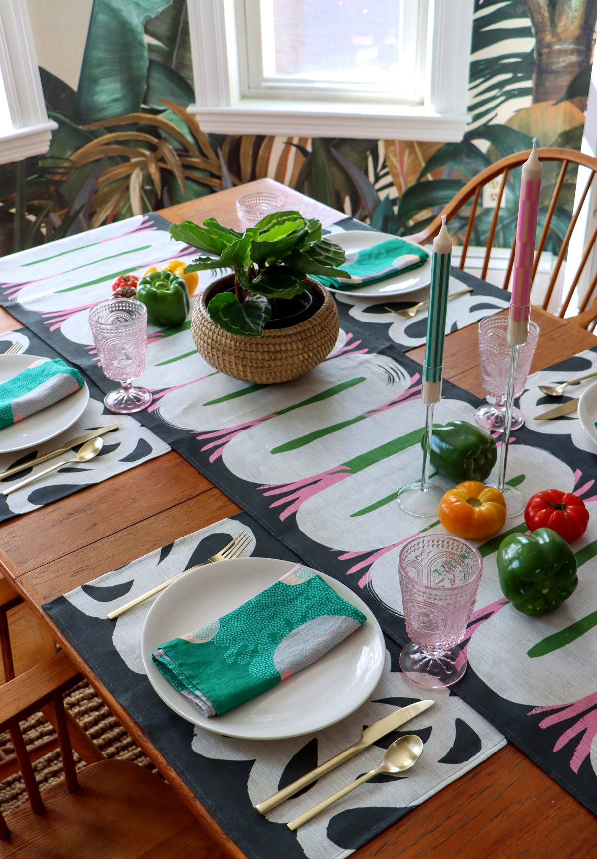 A table set with table linens including green napkins, black and white placemats and an abstract table runner. Designed by artist Leila Simon Hayes.