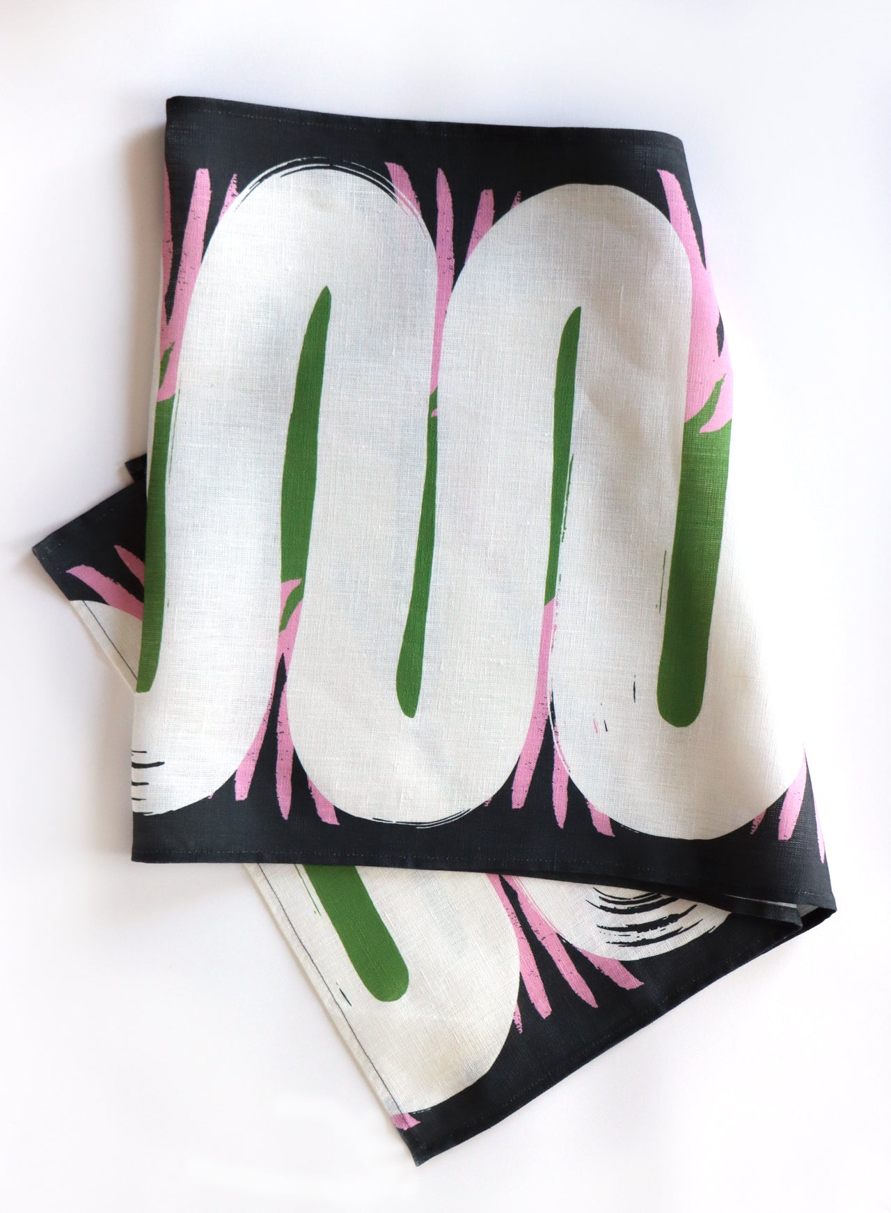 Folded linen table runner with an abstract, organic shape design on a white background. Designed by artist Leila Simon Hayes.