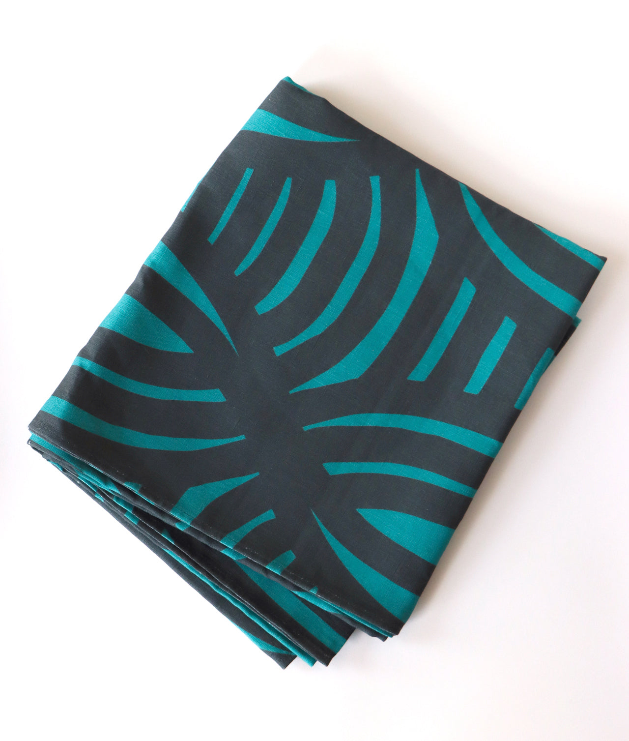 Folded dark blue and light blue tablecloth with a geometric design. Designed by artist Leila Simon Hayes.