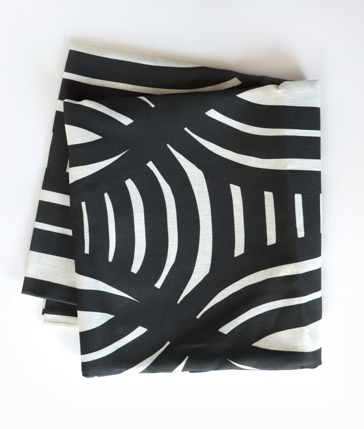 Black and white folded tablecloth on a white background, designed by artist Leila Simon Hayes.