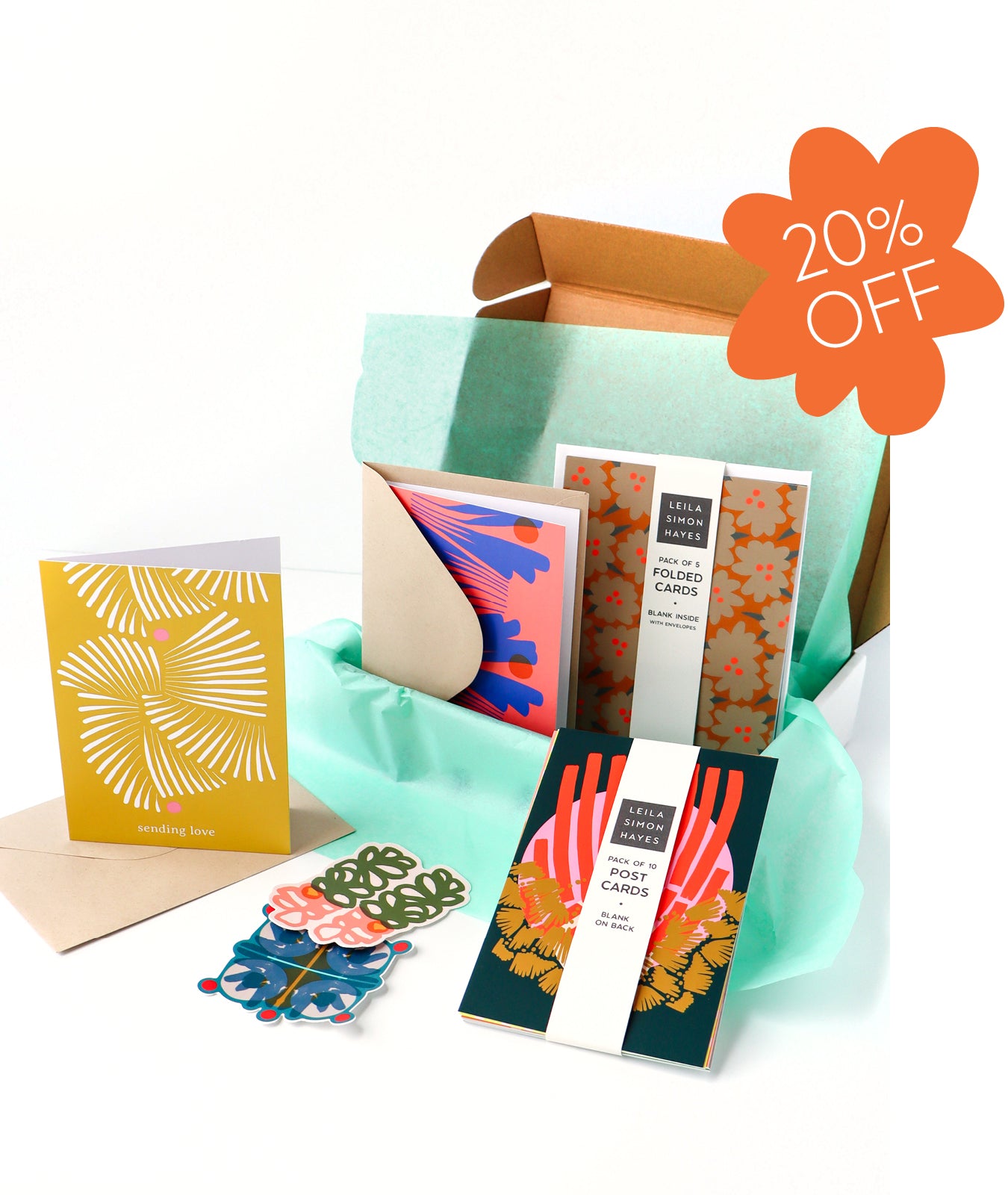 Collection of colorful stationery, designed by artist Leila Simon Hayes. Items including postcards and envelopes with a discount label for 20% off. 