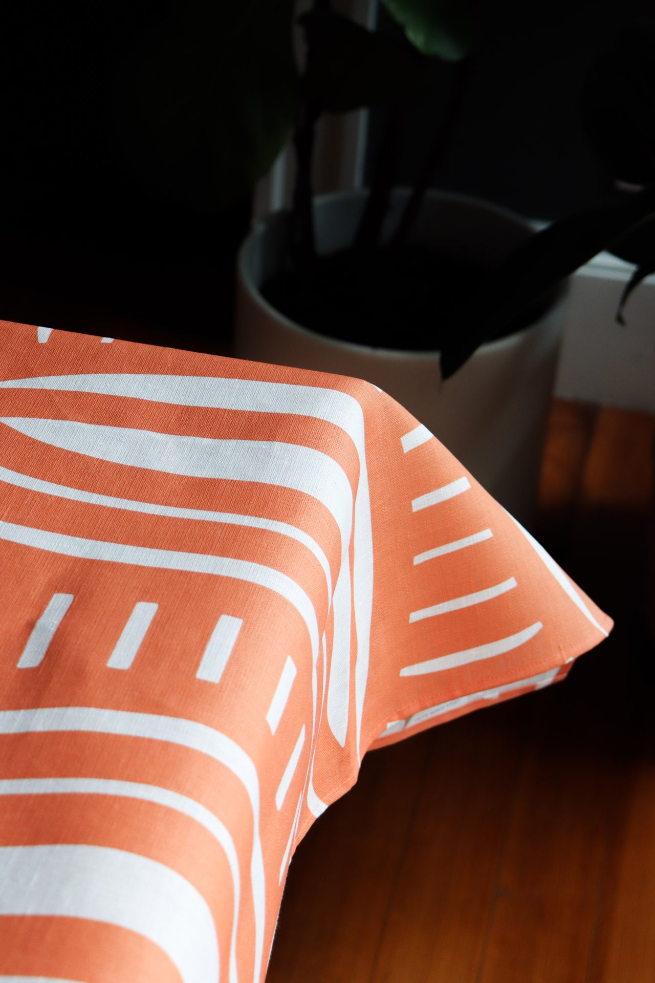 Coral striped tablecloth up close showing what it looks like on a table. Designed by artist Leila Simon Hayes.