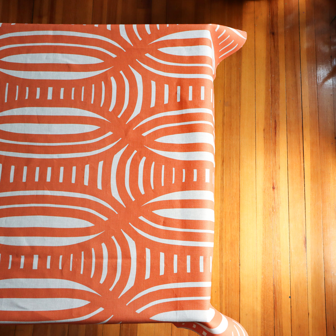 Coral tablecloth with a striped design on a table. Designed by artist Leila Simon Hayes.