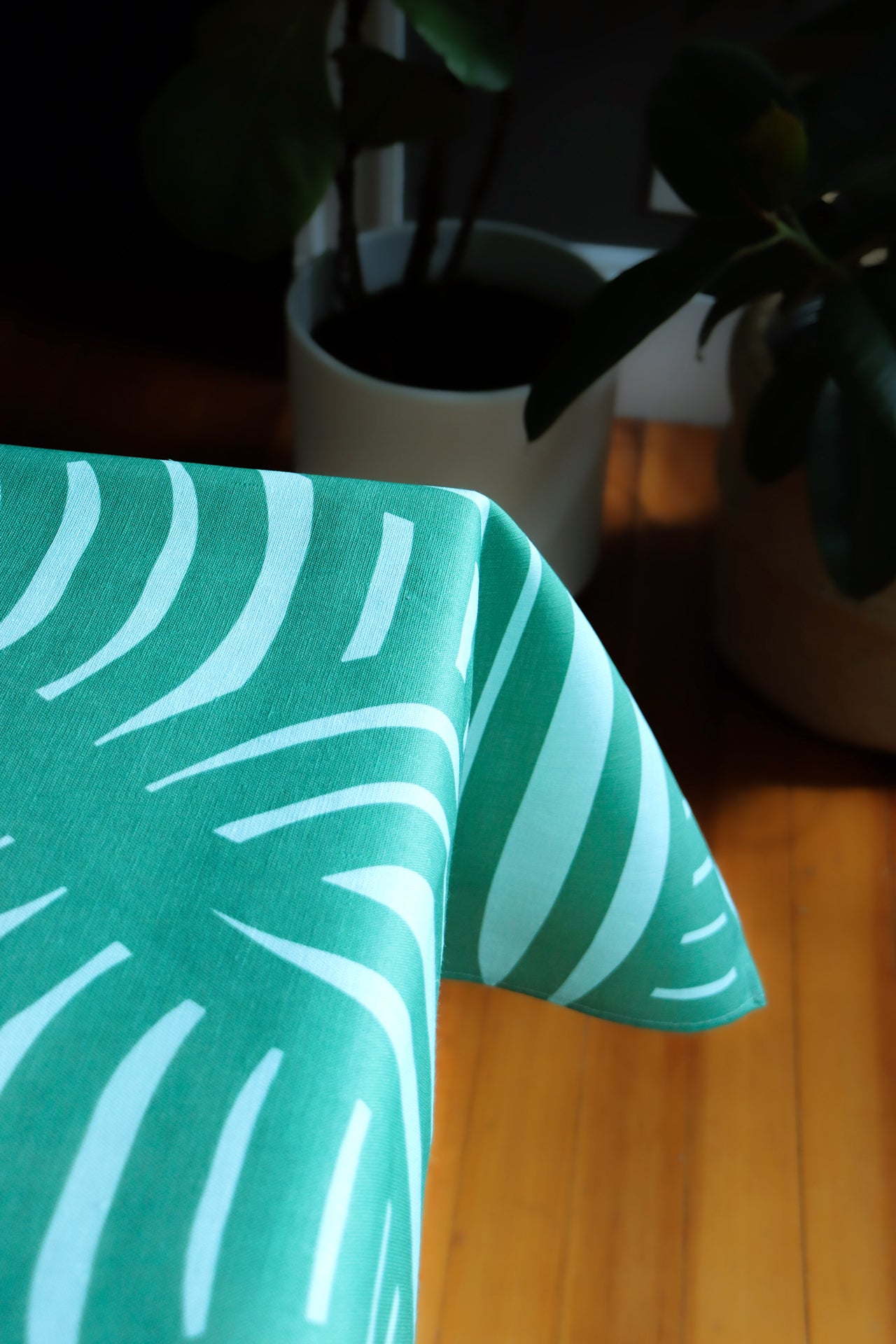 Green tablecloth with geometrical stripe pattern on a wooden surface, designed by artist Leila Simon Hayes.
