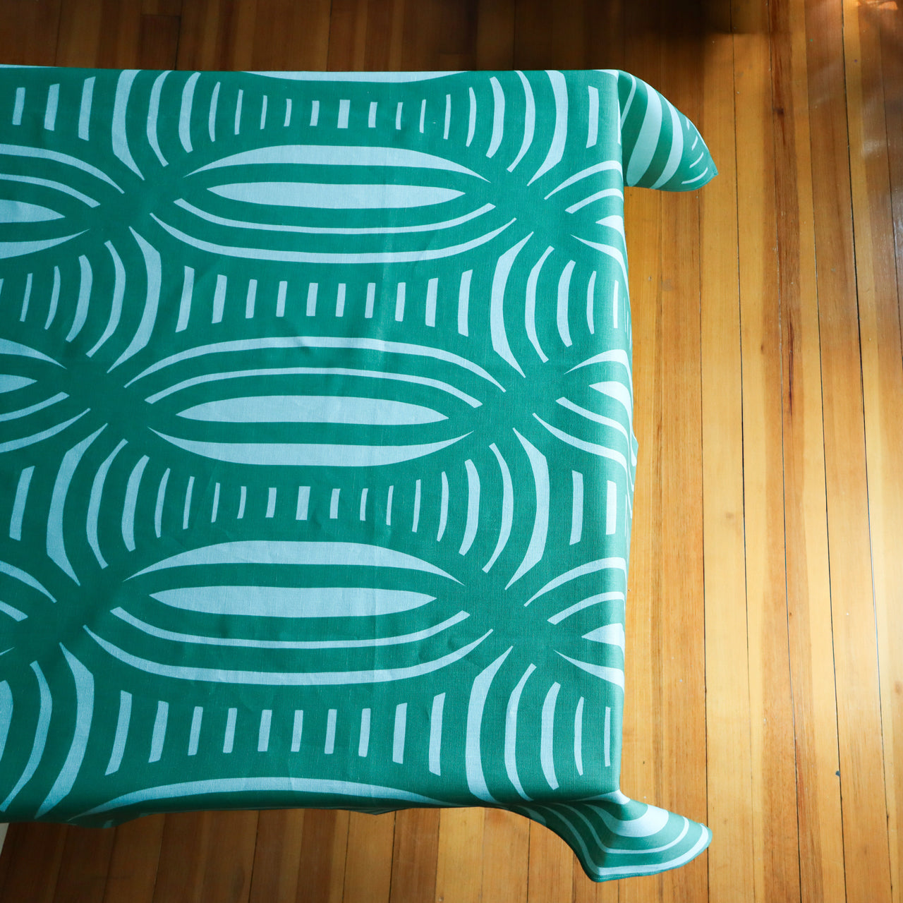 Green geometrical patterned tablecloth on a table, designed by artist Leila Simon Hayes.