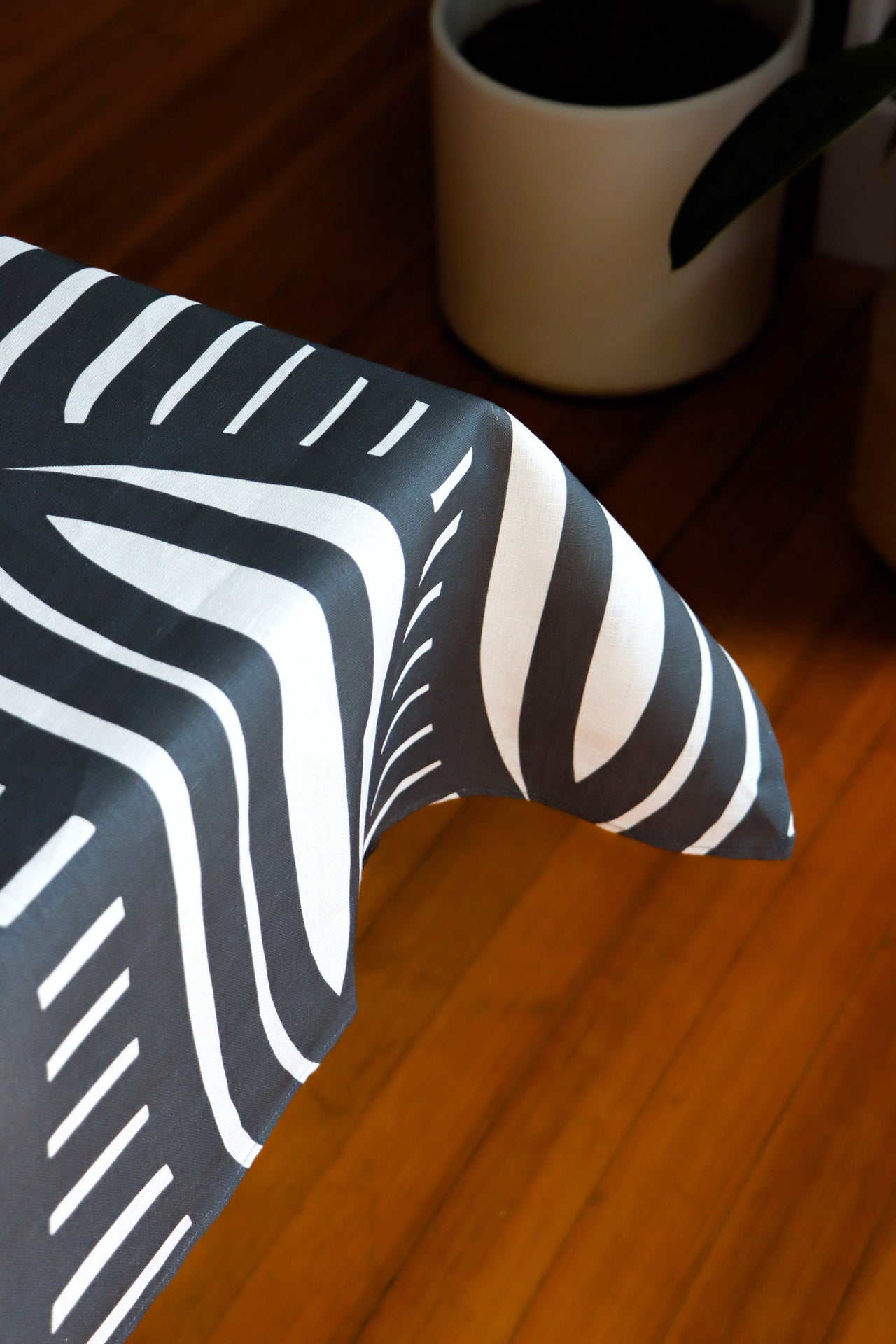 Black and white striped tablecloth on a table with a blurry background. Designed by artist Leila Simon Hayes.