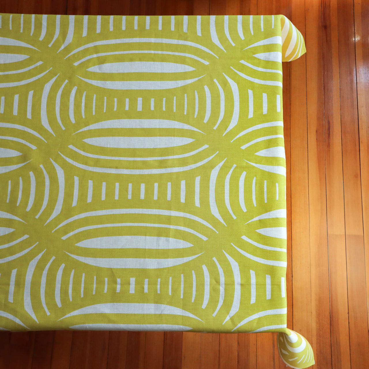 Yellow tablecloth with light yellow geometric pattern on a table, designed by artist Leila Simon Hayes.