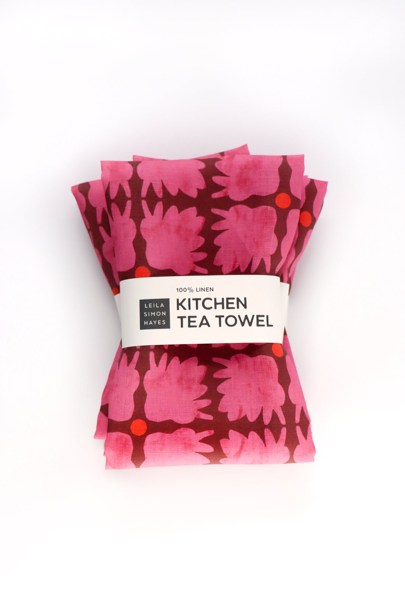 Packaged kitchen tea towels with pink floral pattern on a white background. Designed by artist Leila Simon Hayes.