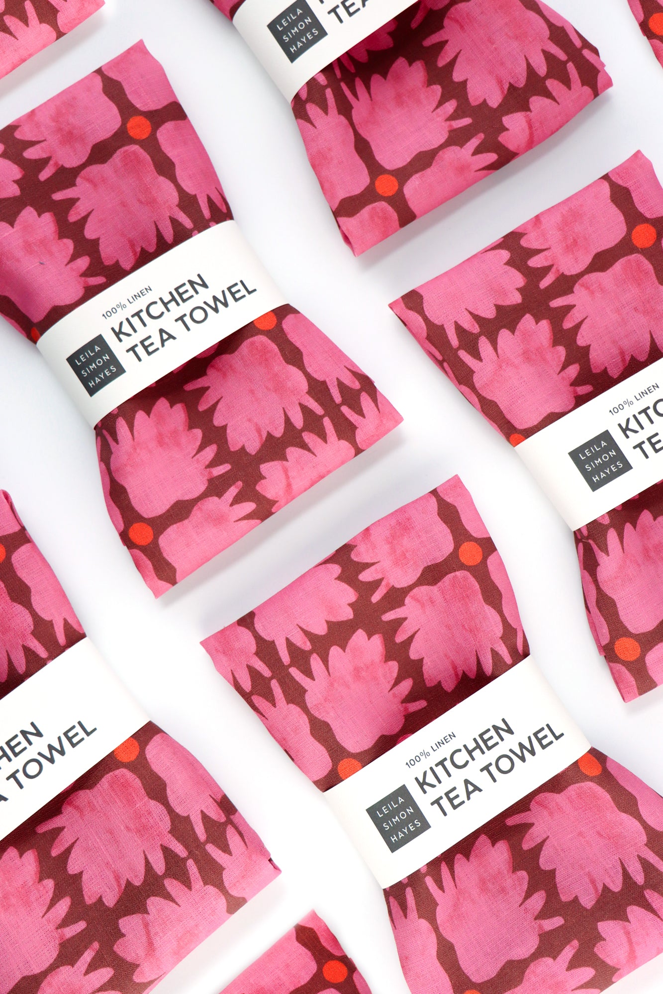 Set of pink floral kitchen tea towels on a white background. Designed by artist Leila Simon Hayes.