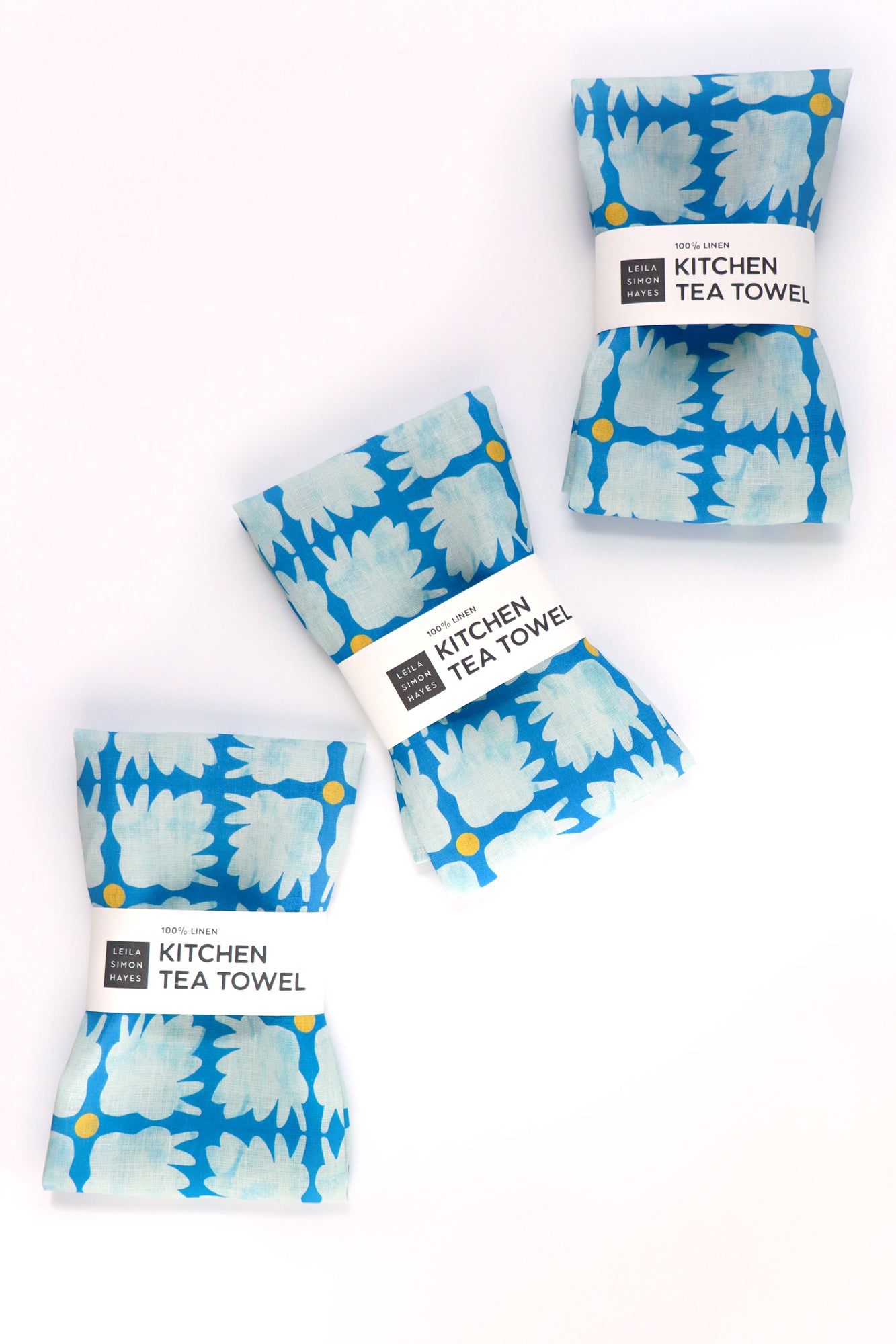 Set of four blue patterned kitchen tea towels on a white background. Designed by artist Leila Simon Hayes.