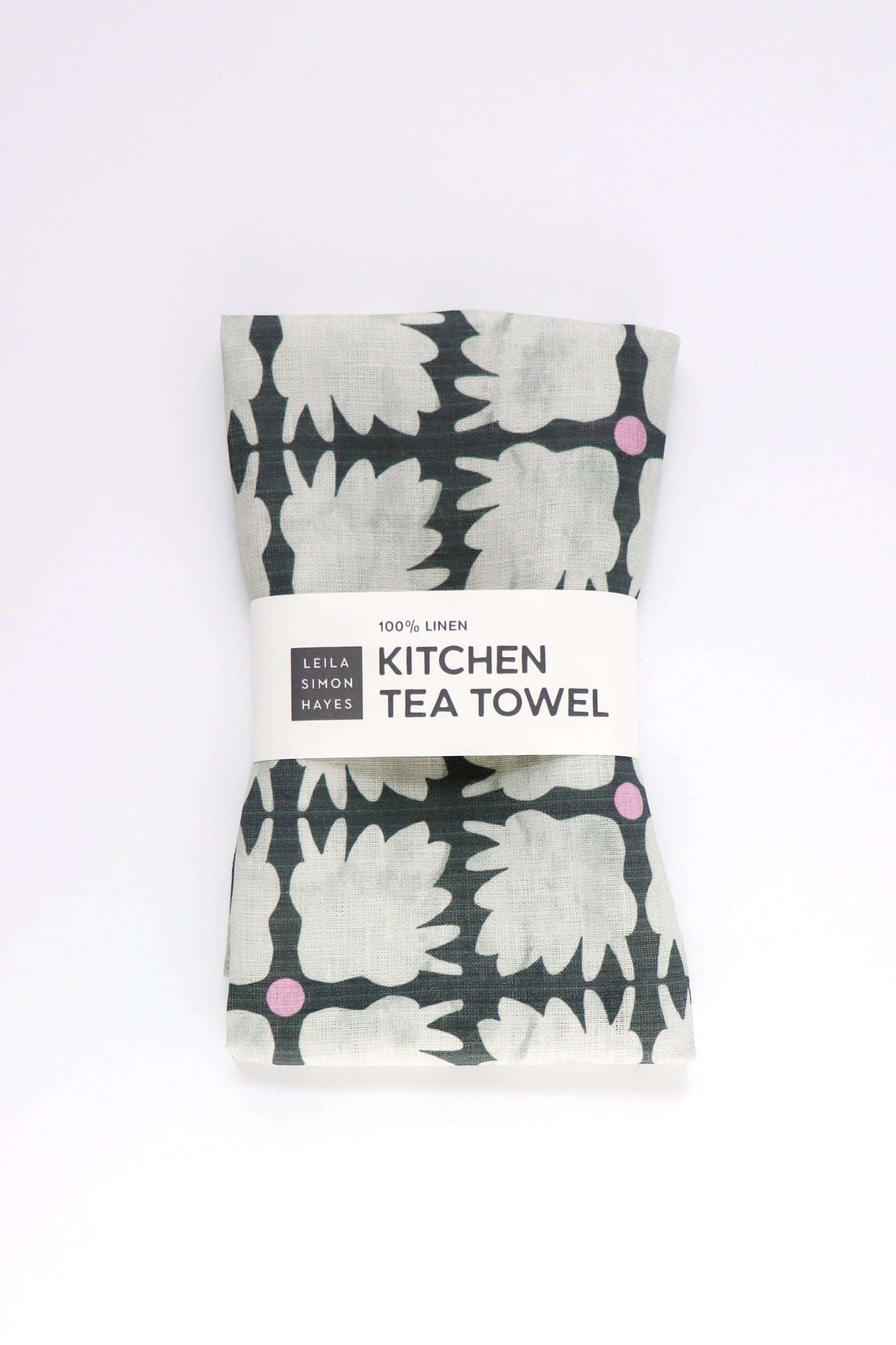 Packaged kitchen tea towel with floral pattern on a white background. Designed by artist Leila Simon Hayes.