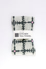 Packaged kitchen tea towel with floral pattern on a white background. Designed by artist Leila Simon Hayes.