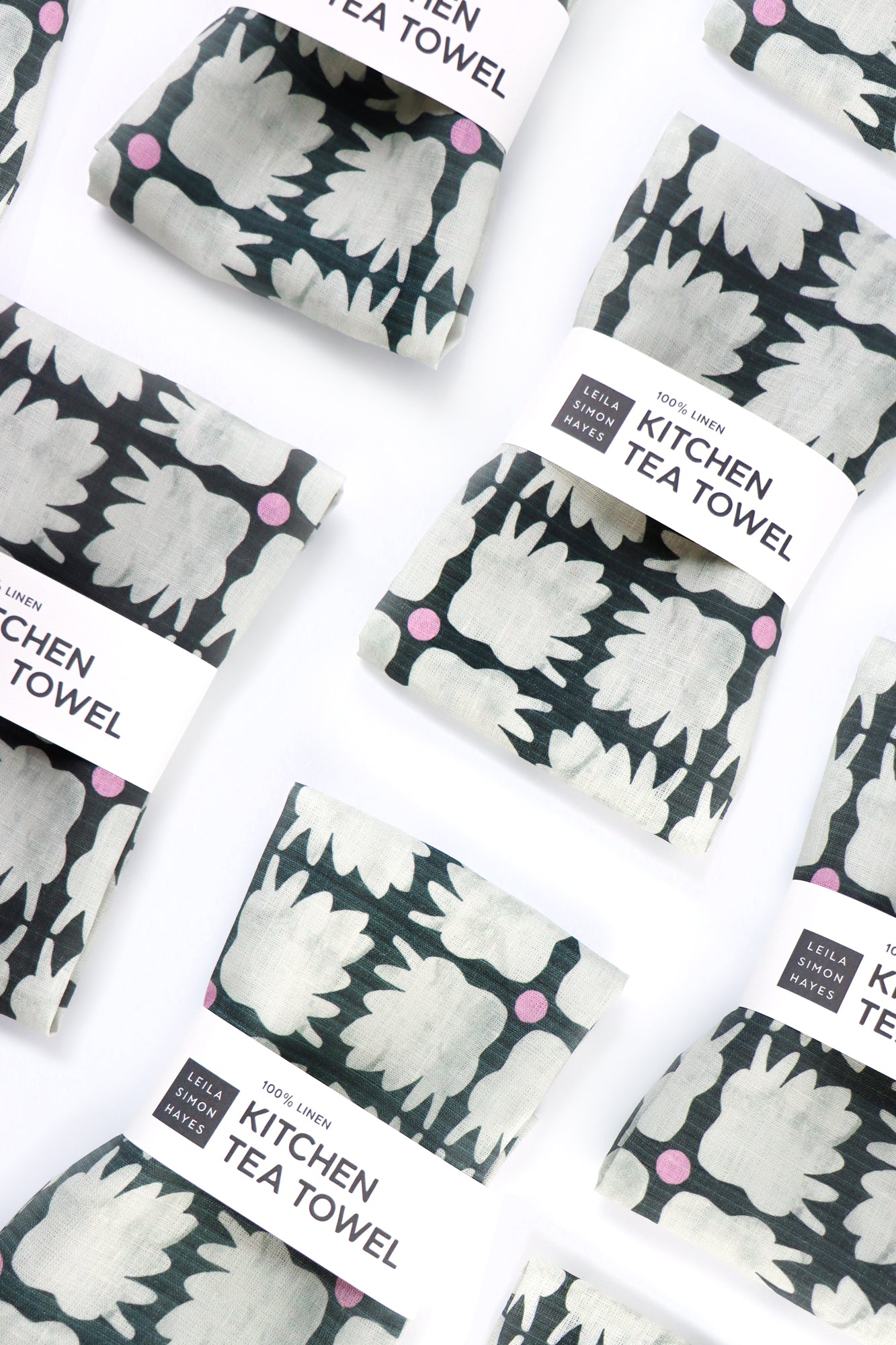Kitchen tea towels with floral pattern and packaged in "100% Linen" label with branding on white background. Designed by artist Leila Simon Hayes.