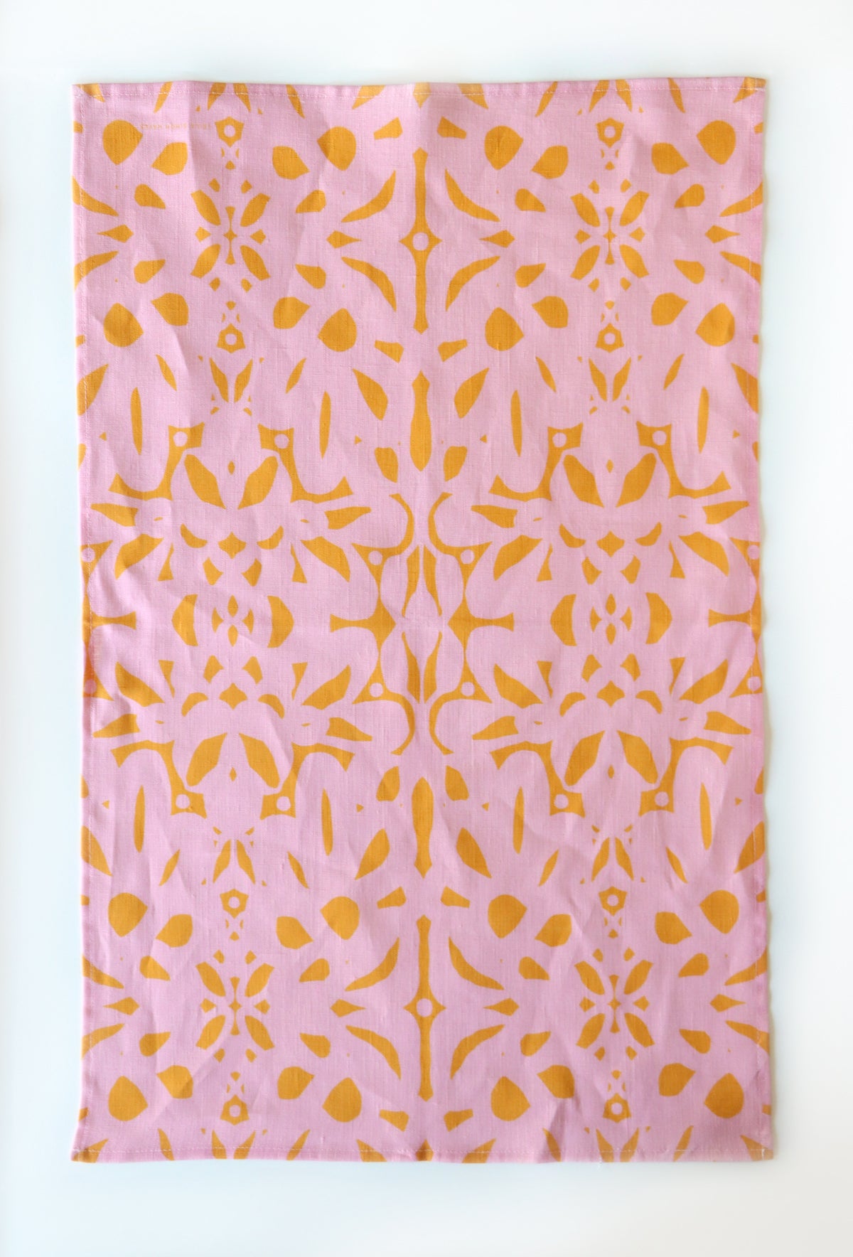 Pink tea towel with yellow abstract pattern on a white background. Designed by artist Leila Simon Hayes.
