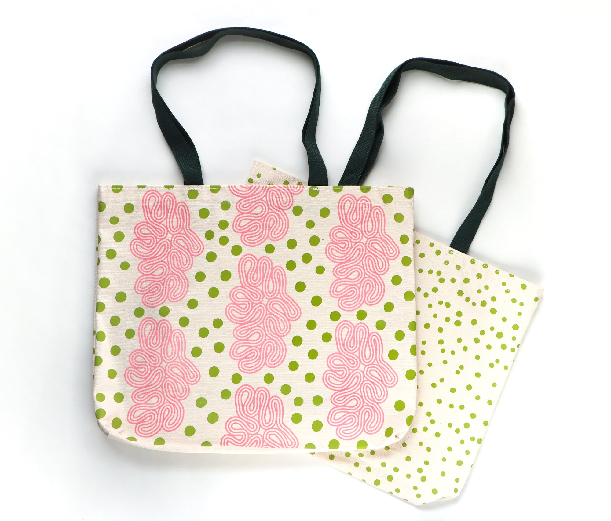 Tote bag with pink floral and green polka dot pattern on one side and green polka dots on a cream colored tote. Designed by artist Leila Simon Hayes.