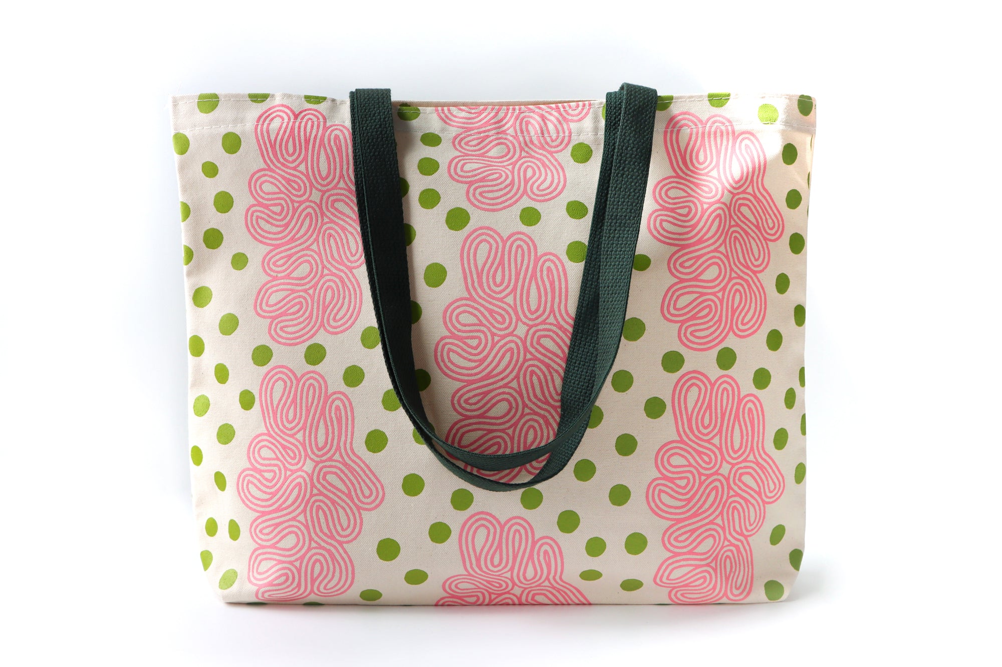Tote bag with pink abstract patterns and green polka dots on a white background. Designed by artist Leila Simon Hayes.