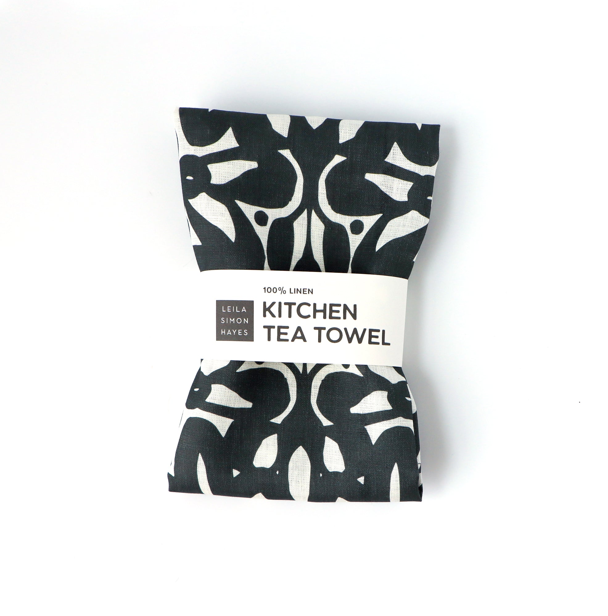 Black and white patterned kitchen tea towel packaging on a white background. Designed by artist Leila Simon Hayes.