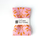 Pink kitchen tea towel with orange patterns on a white background. Designed by artist Leila Simon Hayes.