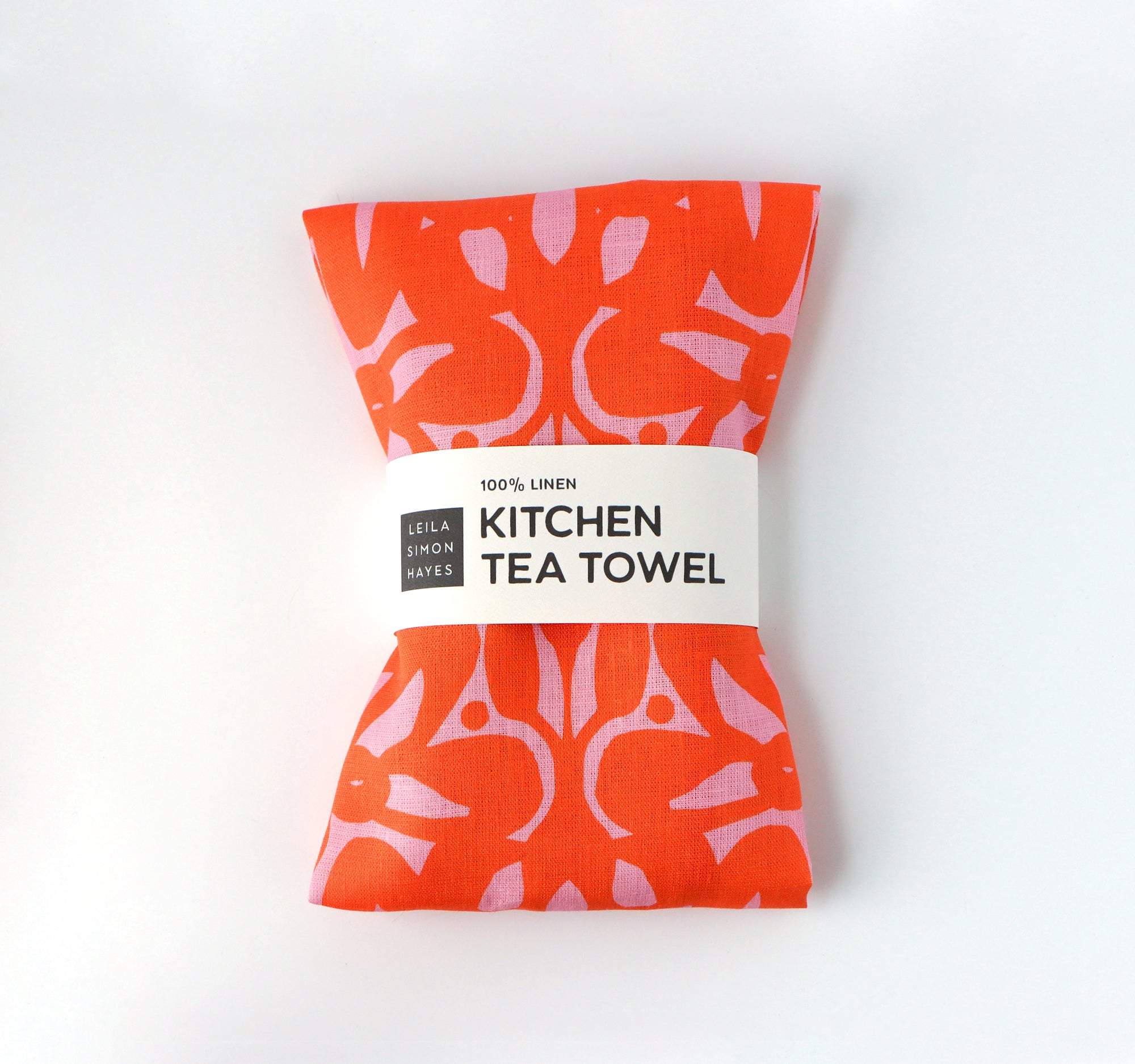 Orange kitchen tea towel with pink pattern on a white background. Designed by artist Leila Simon Hayes.